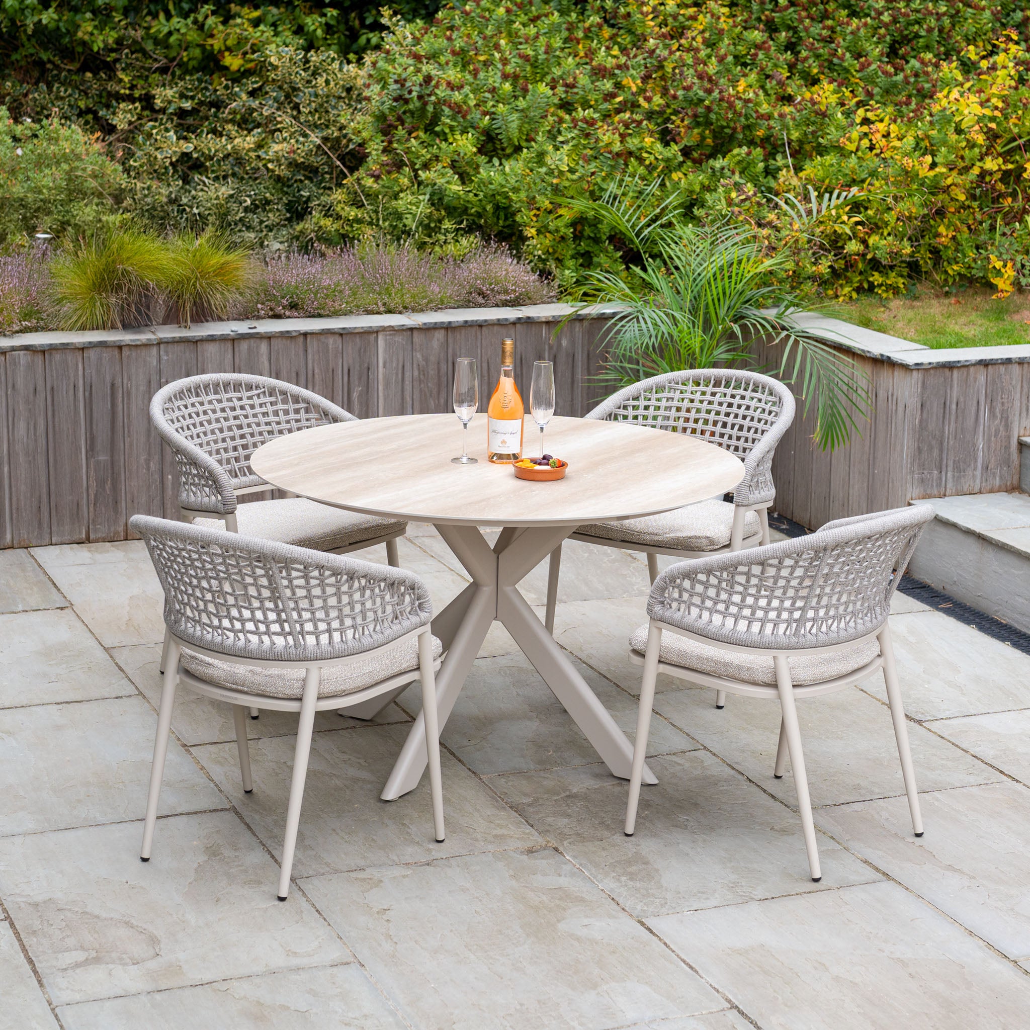 The Kalama 4 Seat Round Rope Dining Set with Albatross Table in Oatmeal is perfect for creating a welcoming garden dining space on your stone terrace—ideal outdoor furniture for relaxing evenings.