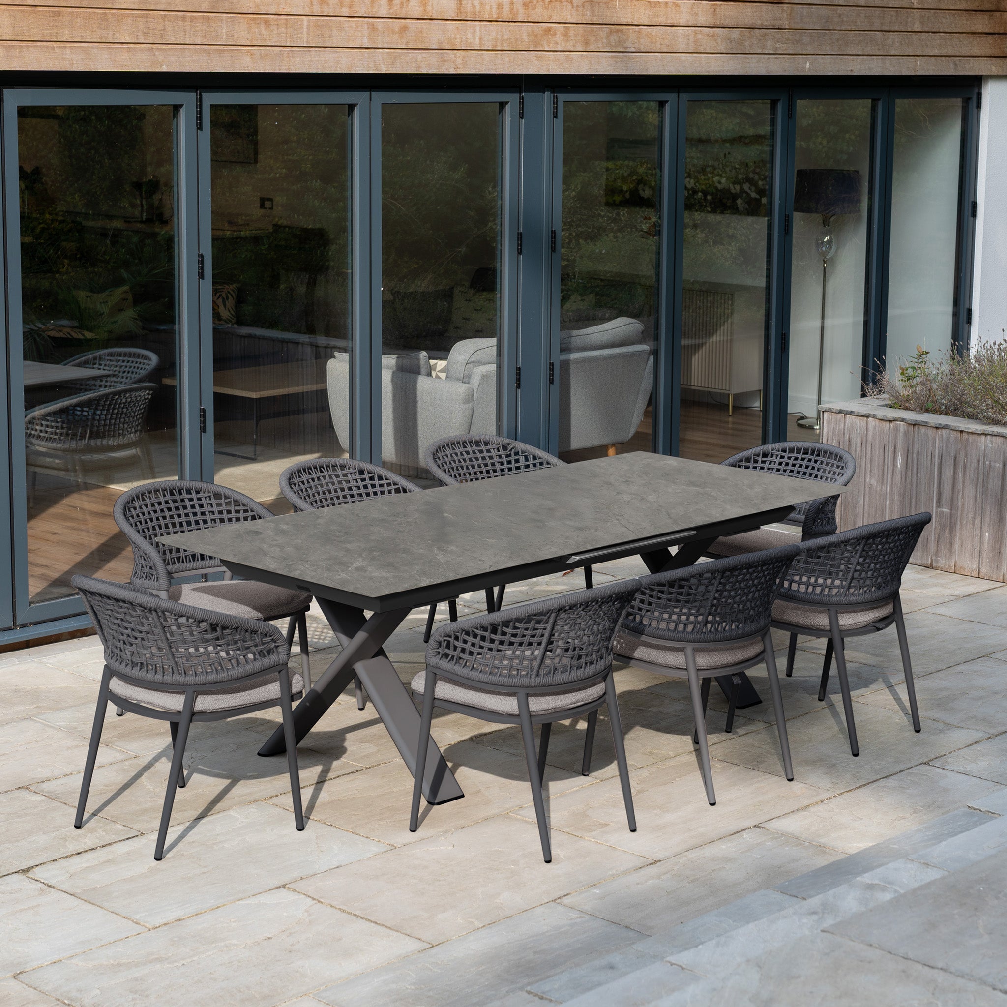 The Kalama 8 Seat Rope Dining Set with Albatross Extending Table in Truffle features stylish woven chairs and a spacious rectangular table, perfect for enhancing your stone patio by the glass doors.