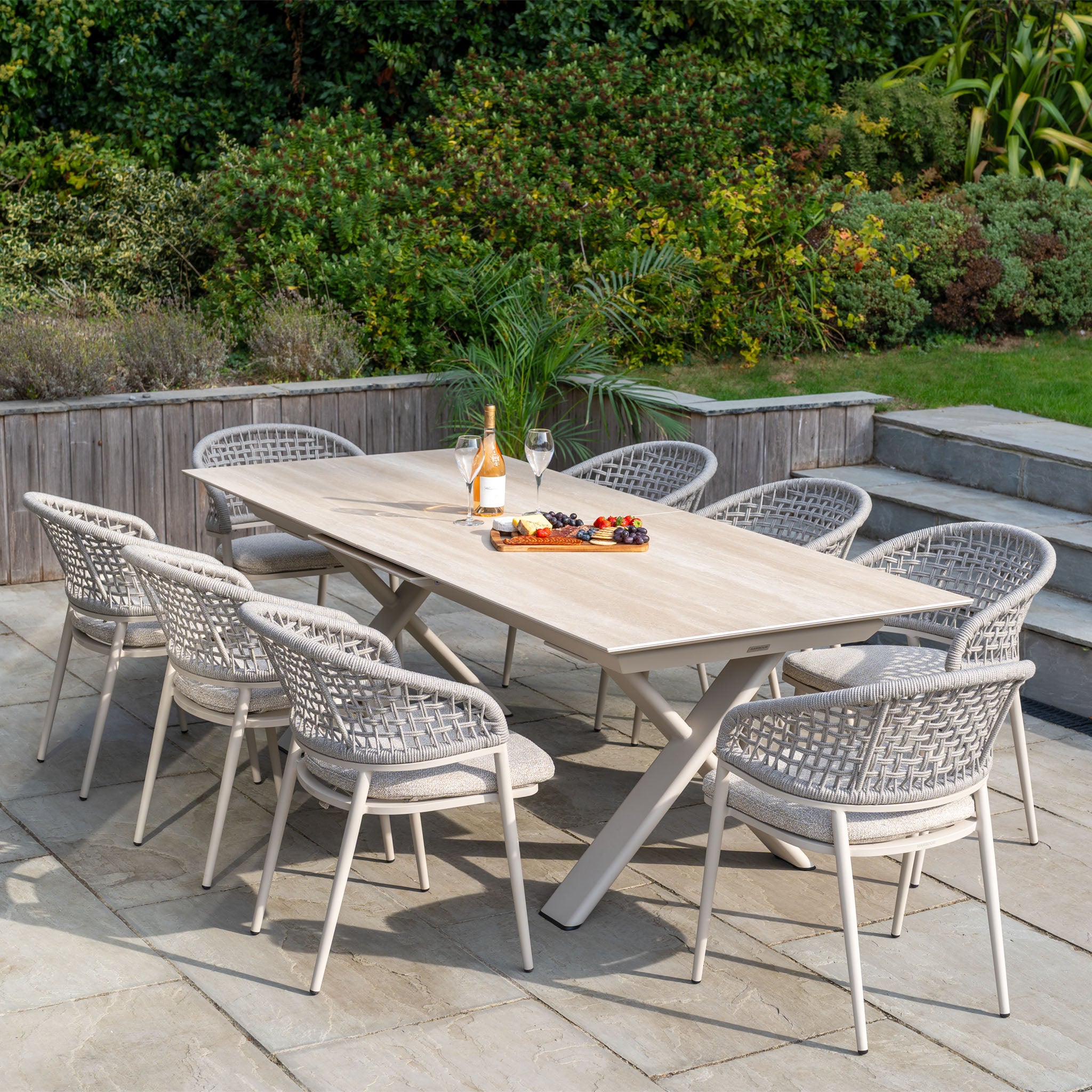 Modern outdoor dining with the Kalama 8 Seat Rope Dining Set featuring an Albatross Extending Table in Oatmeal, elegantly arranged on a patio with wine, glasses, and snacks.