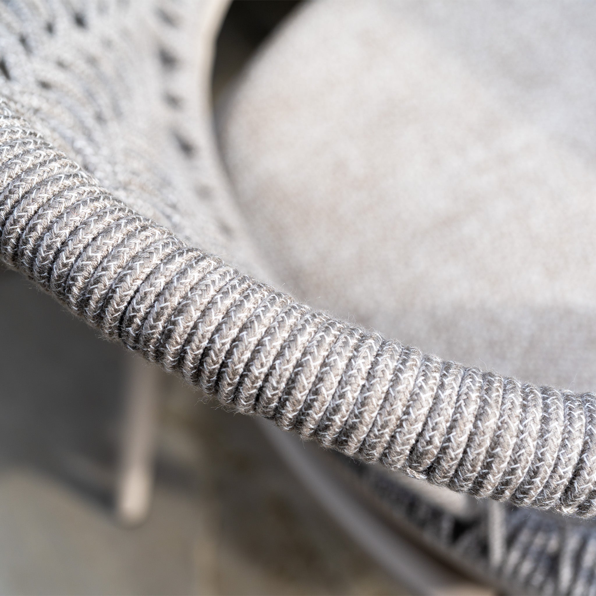 Close-up of a woven gray chair armrest from the Kalama 8 Seat Rope Dining Set with Albatross Extending Table in Oatmeal, showcasing the detailed texture and premium pattern typical of high-quality outdoor dining furniture.