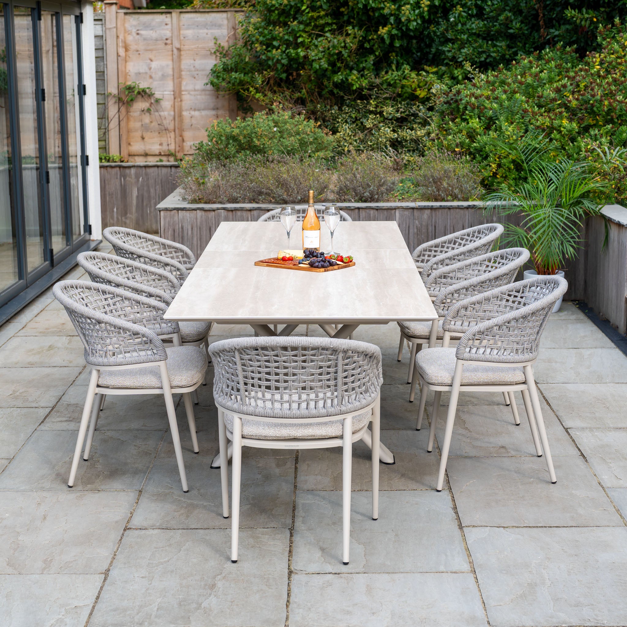 The Kalama 8 Seat Rope Dining Set with Albatross Extending Table in Oatmeal includes eight woven chairs and a spacious table, creating an inviting outdoor dining arrangement for your patio.