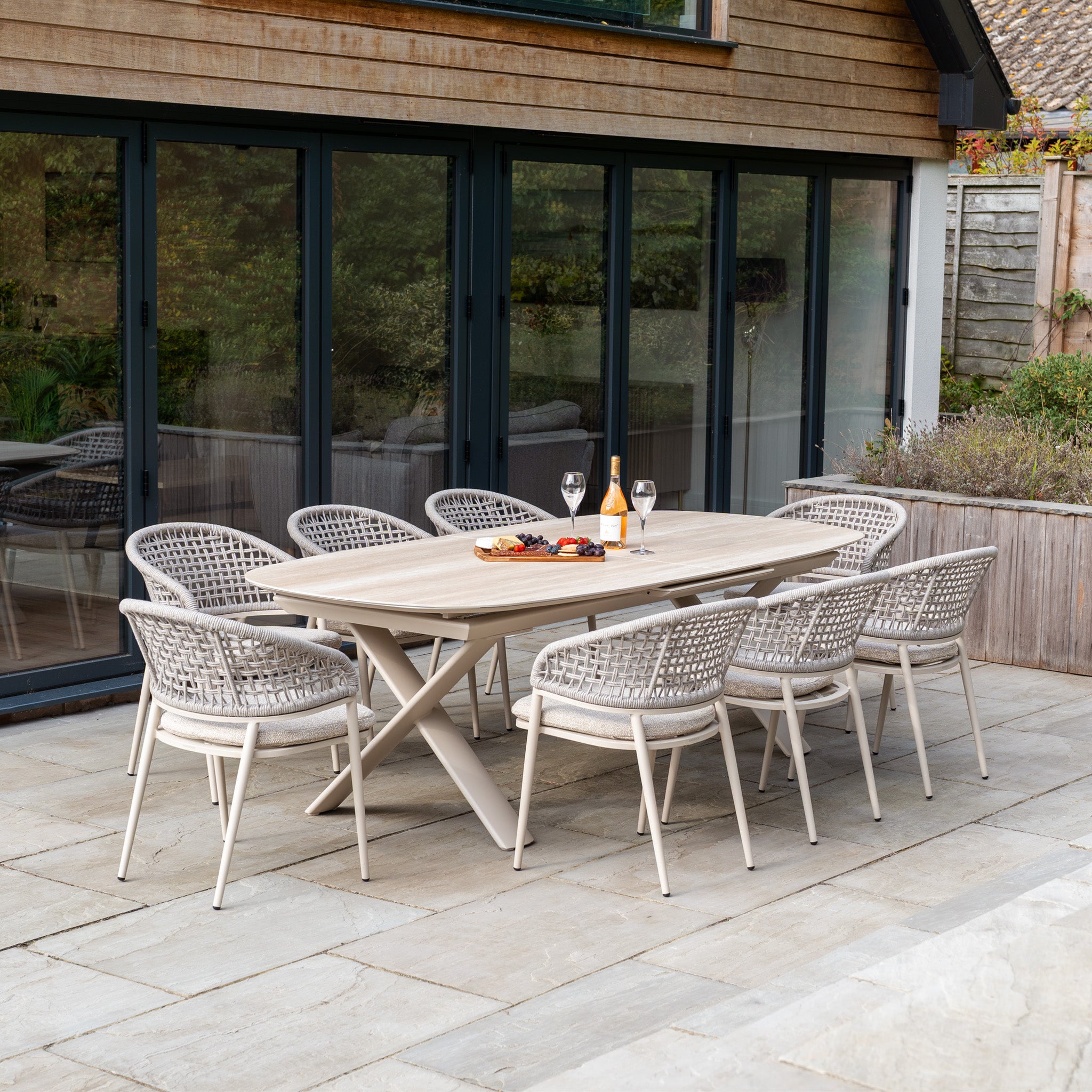 Host gatherings in style with the Kalama 8 Seat Oval Rope Dining Set with Albatross Extending Table in Oatmeal, featuring eight woven chairs and a spacious table, perfect for wine and snacks on your patio.