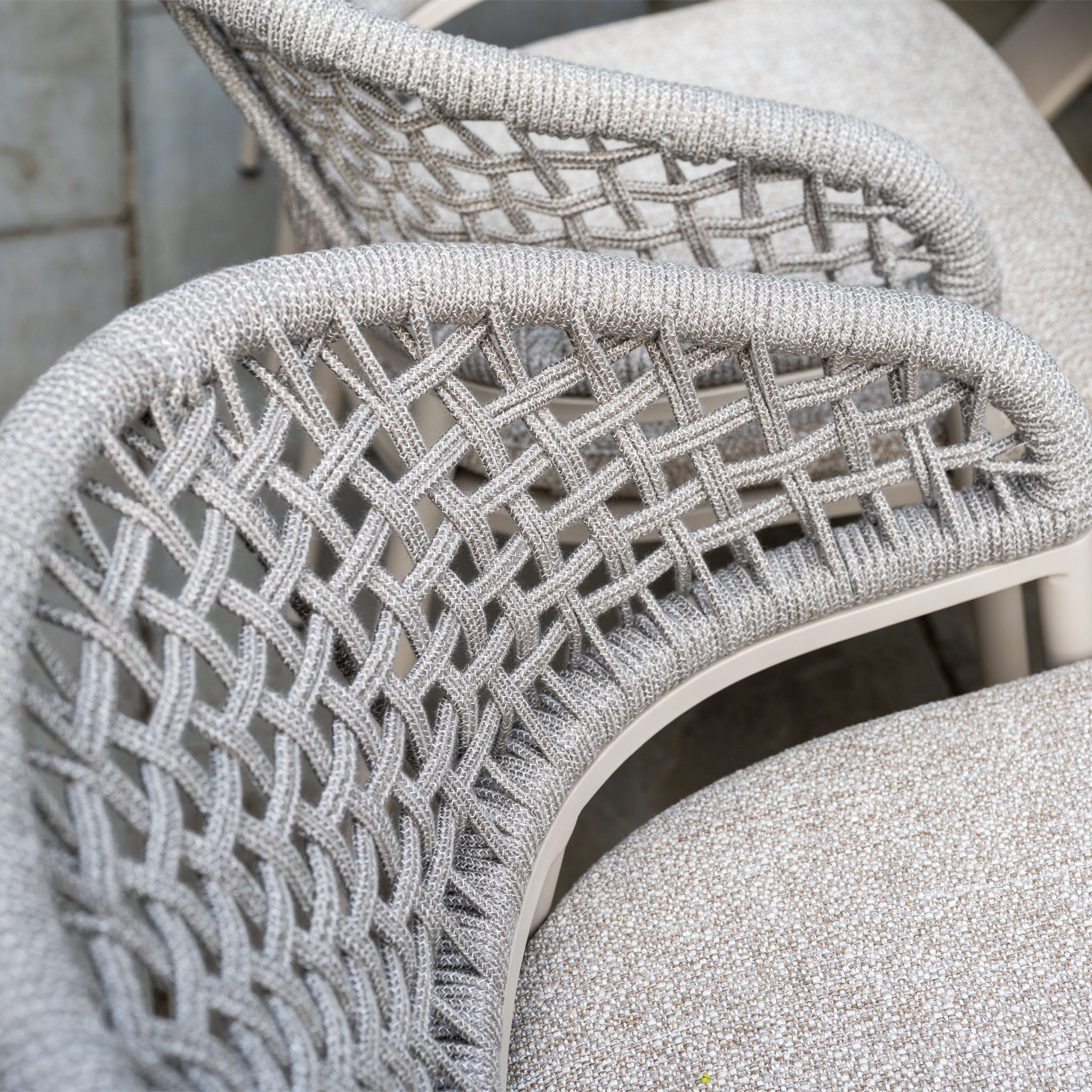 Close-up of two gray woven chairs with crisscross backrests, part of the Kalama 8 Seat Oval Rope Dining Set with Albatross Extending Table in Oatmeal—an elegant choice for stylish outdoor gatherings.