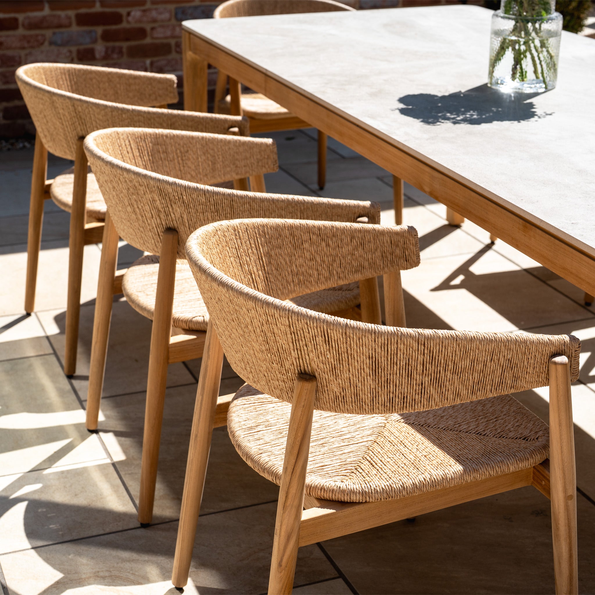 The Lucca 8 Seat Dining Set with Ceramic Top Table in Natural Weave features woven wood chairs and a rectangular ceramic-top table, ideal for sunny, stylish outdoor gatherings.