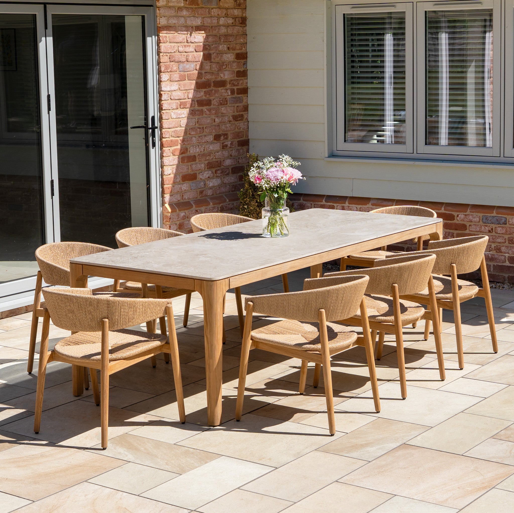 The Lucca 8 Seat Dining Set with Ceramic Top Table in Natural Weave offers stylish outdoor seating for eight, making it an ideal choice for gatherings by large windows.