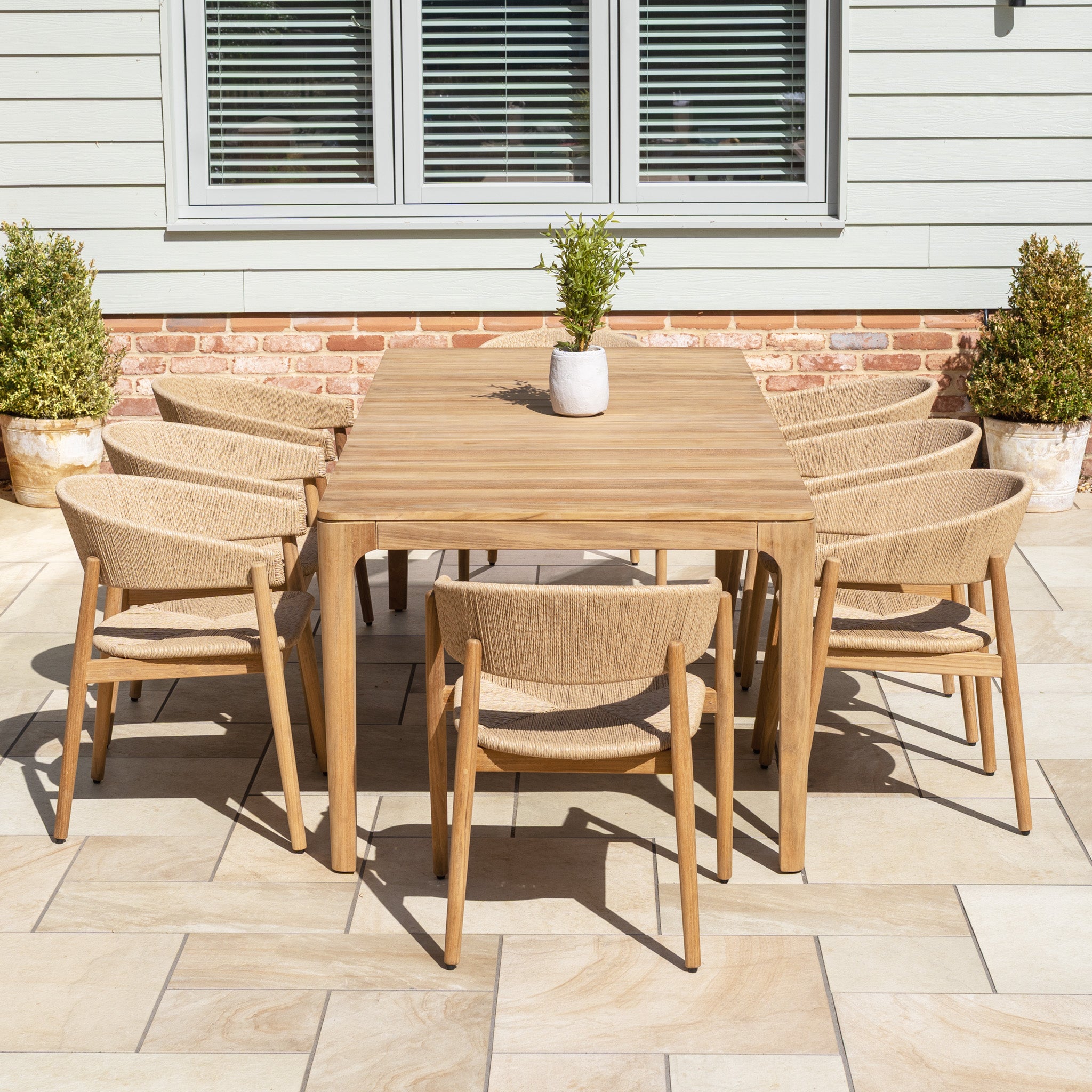 The Lucca 8 Seat Dining Set with Teak Table in Natural Weave seats eight and features teak and wicker, bringing lasting style and functionality to your outdoor space. It's perfect for enhancing patios outside homes with classic siding and windows.