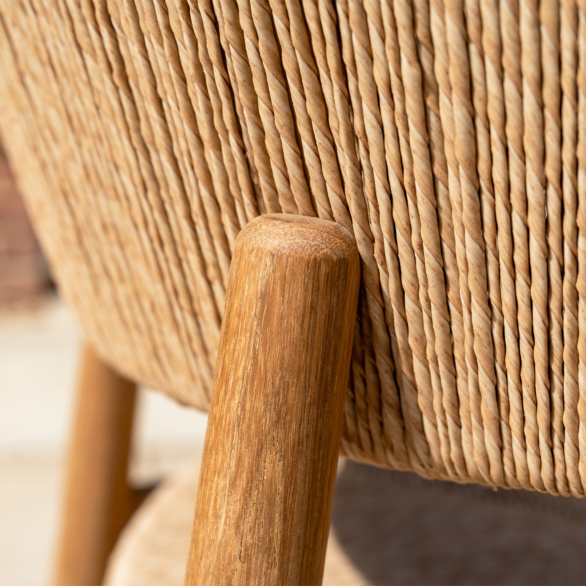 Close-up of a wooden chair leg and woven rope seat from the Lucca 8 Seat Dining Set with Teak Table in Natural Weave, showcasing the texture and craftsmanship of these hand-woven wicker chairs.