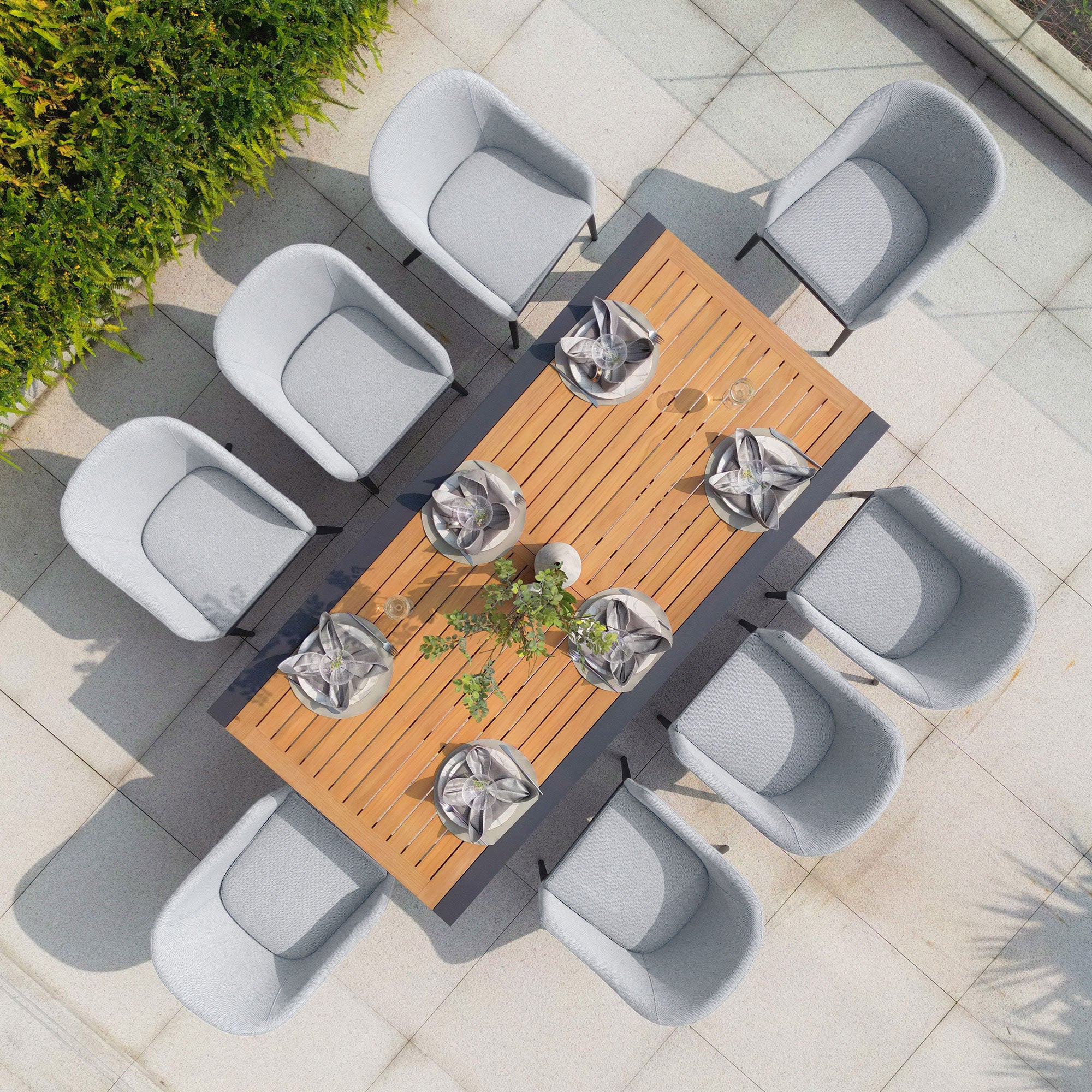 Top view of the Luna 8 Seat Outdoor Fabric Extending Teak Dining Set in Oyster Grey, featuring eight gray chairs adorned with folded napkins and glassware. The maintenance-free design ensures it remains pristine, perfect for any occasion.