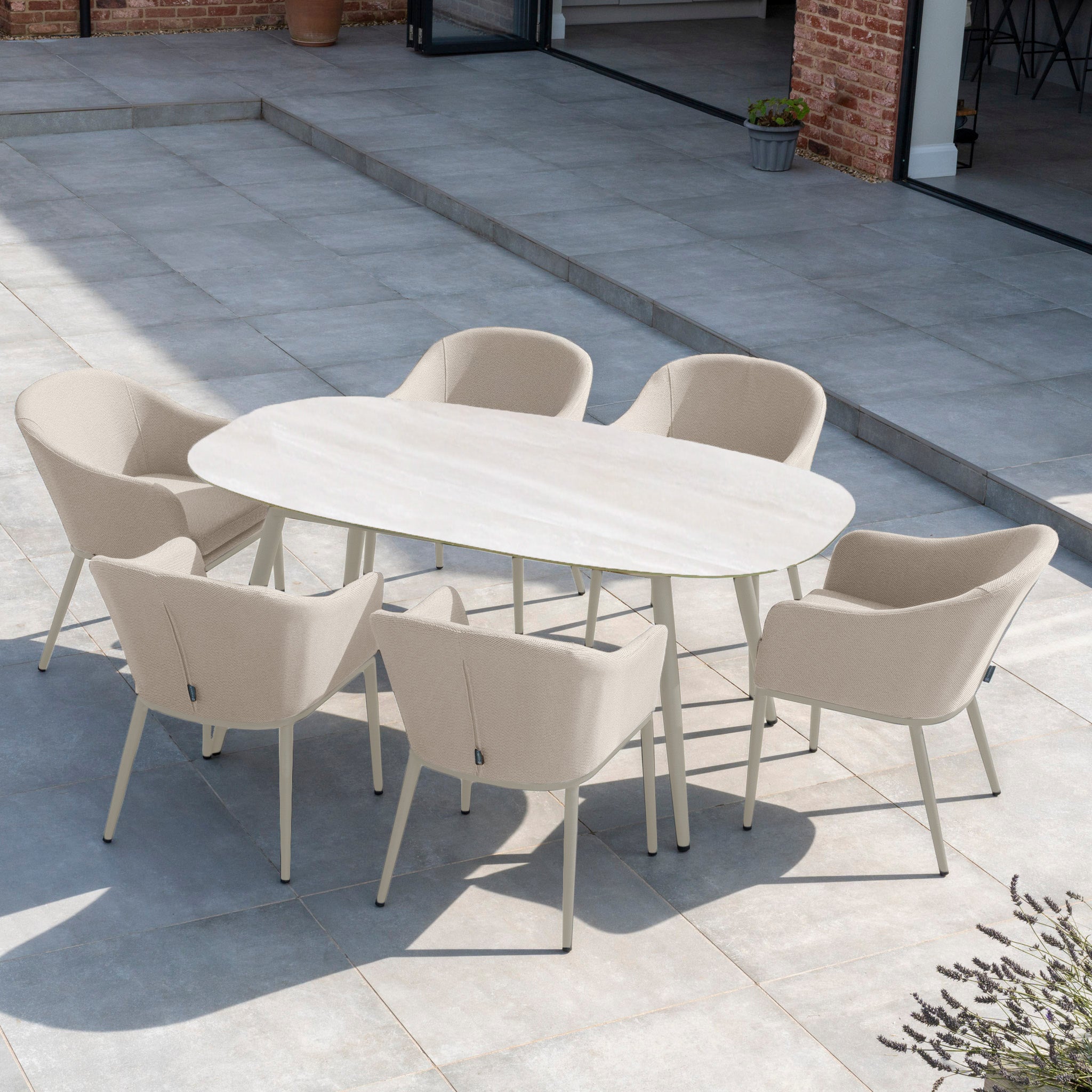 The Luna 6 Seat Outdoor Fabric Oval Ceramic Dining Set in Fawn features durable all-weather materials, beige Luna fabric chairs, and an oval ceramic table—ideal for your light gray tiled patio.