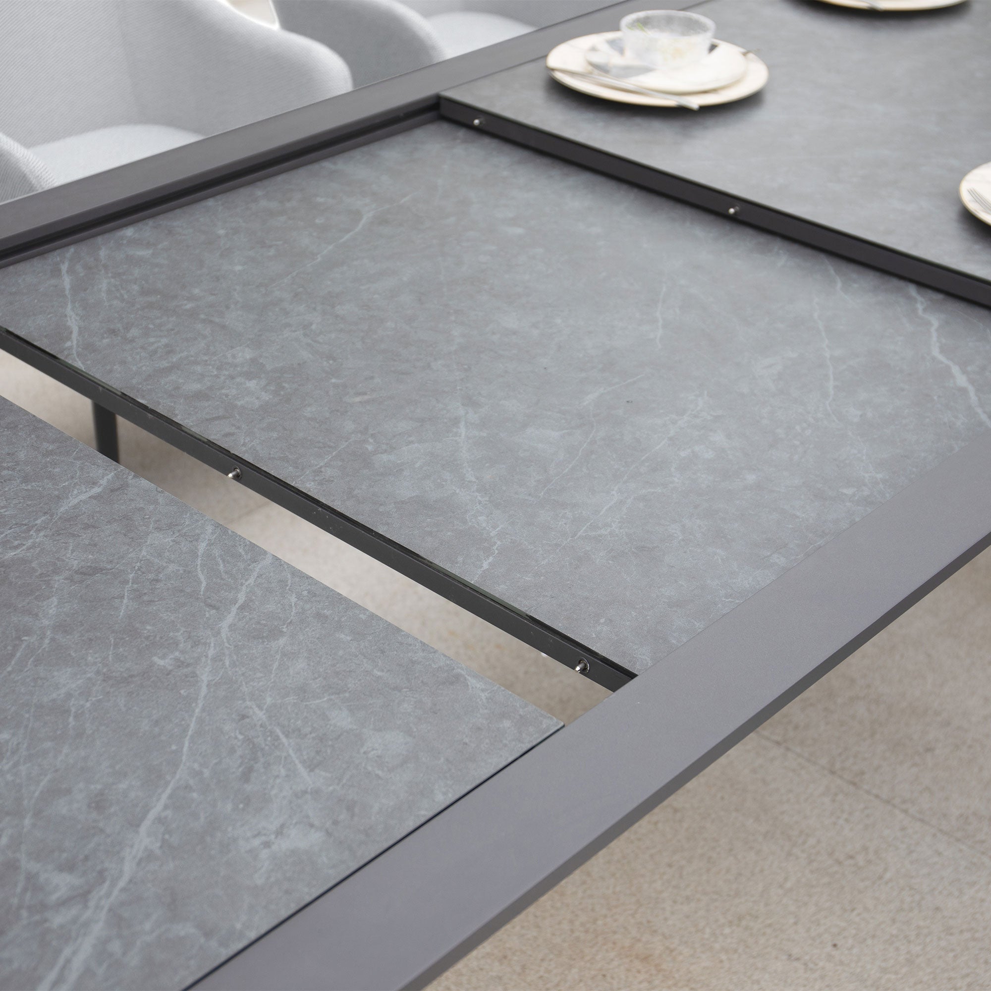 A close-up view of the Luna 8 Seat Outdoor Fabric Extending Ceramic Dining Set in Oyster Grey, elegantly arranged with four plates and teacups for dining.