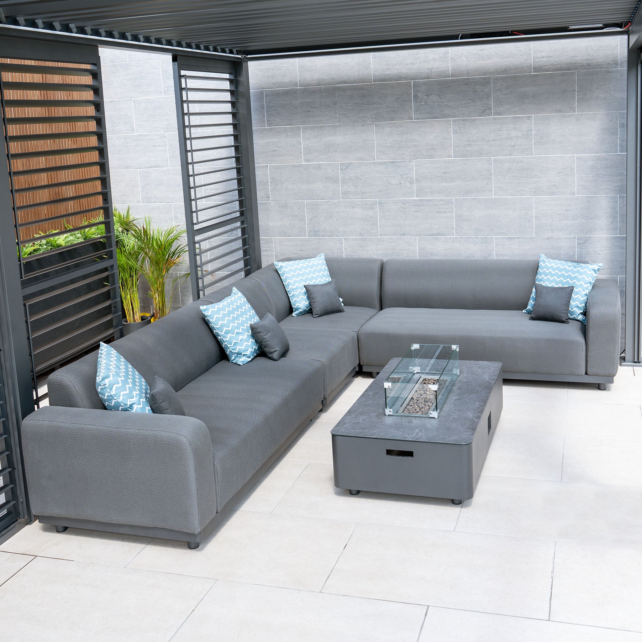 The Luna Outdoor Fabric Large Corner Group Set in Grey features blue fabric cushions and a firepit coffee table, offering a stylish outdoor experience similar to the Harbour Lifestyle Luna Corner Group Set.