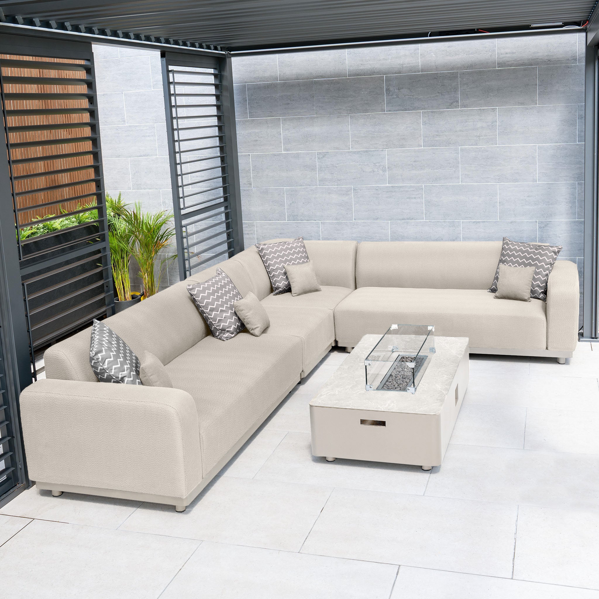 Outdoor patio with a Luna Outdoor Fabric Large Corner Group Set in fawn, featuring a stain-proof firepit coffee table and patterned cushions, nestled under a slatted pergola.