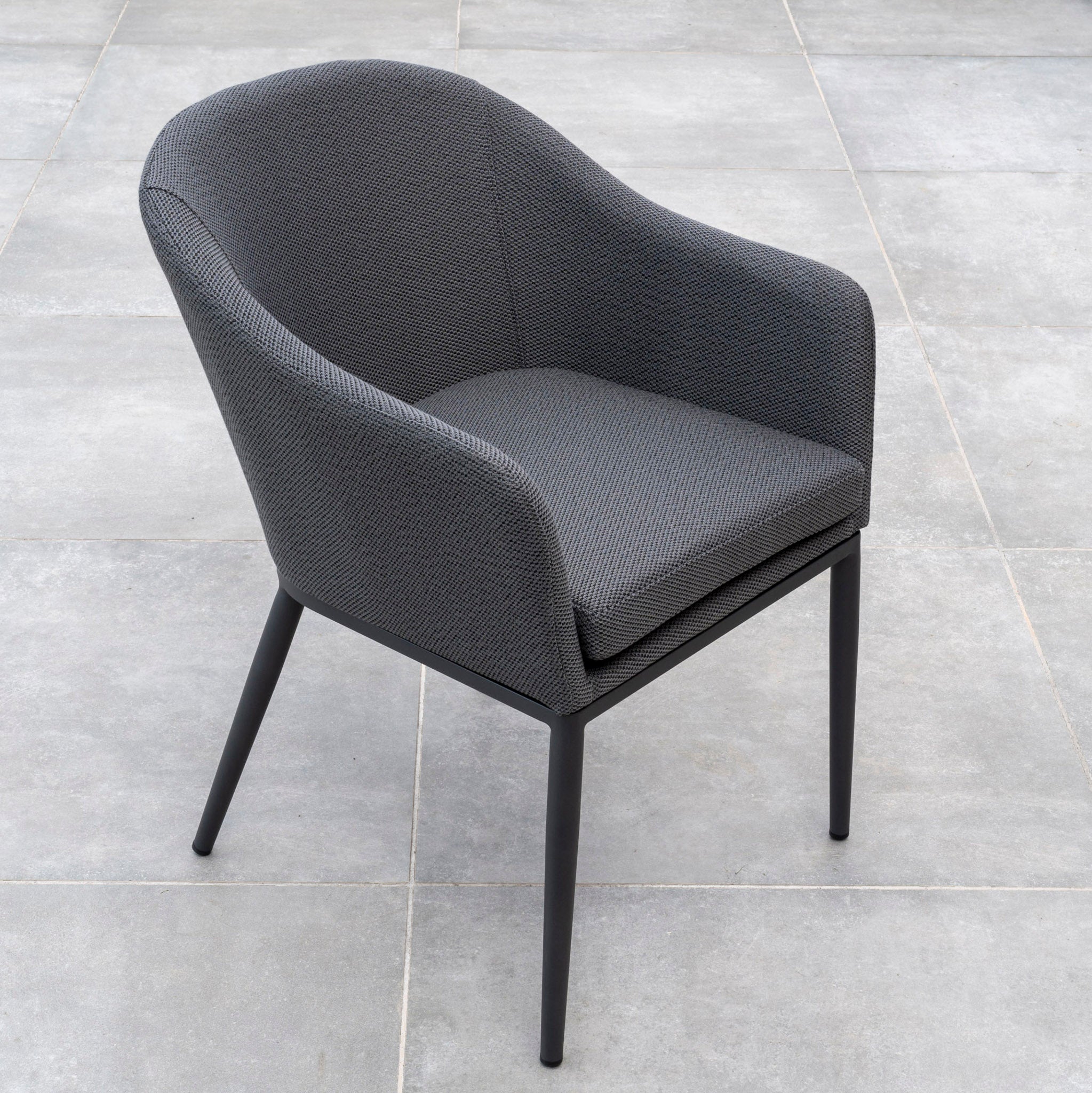 A Luna 8 Seat Outdoor Fabric Rectangular Ceramic Firepit Dining Set in Grey, featuring modern gray upholstered chairs with sleek black legs crafted from all-weather material and Luna outdoor fabric, is placed on a gray tiled floor.
