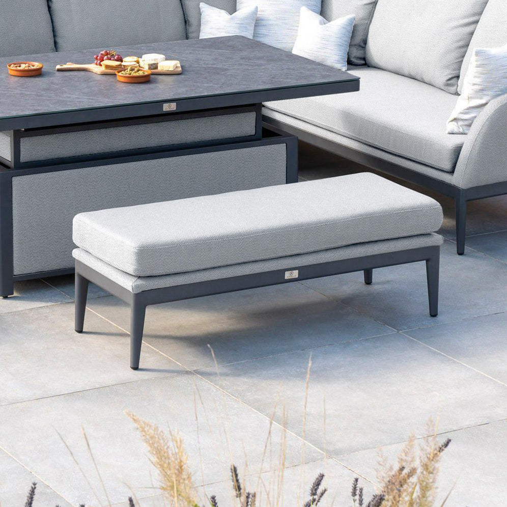 Modern outdoor patio set featuring the Luna Bench in Oyster Grey with cushions, a snack table, and a sofa on a tiled patio.