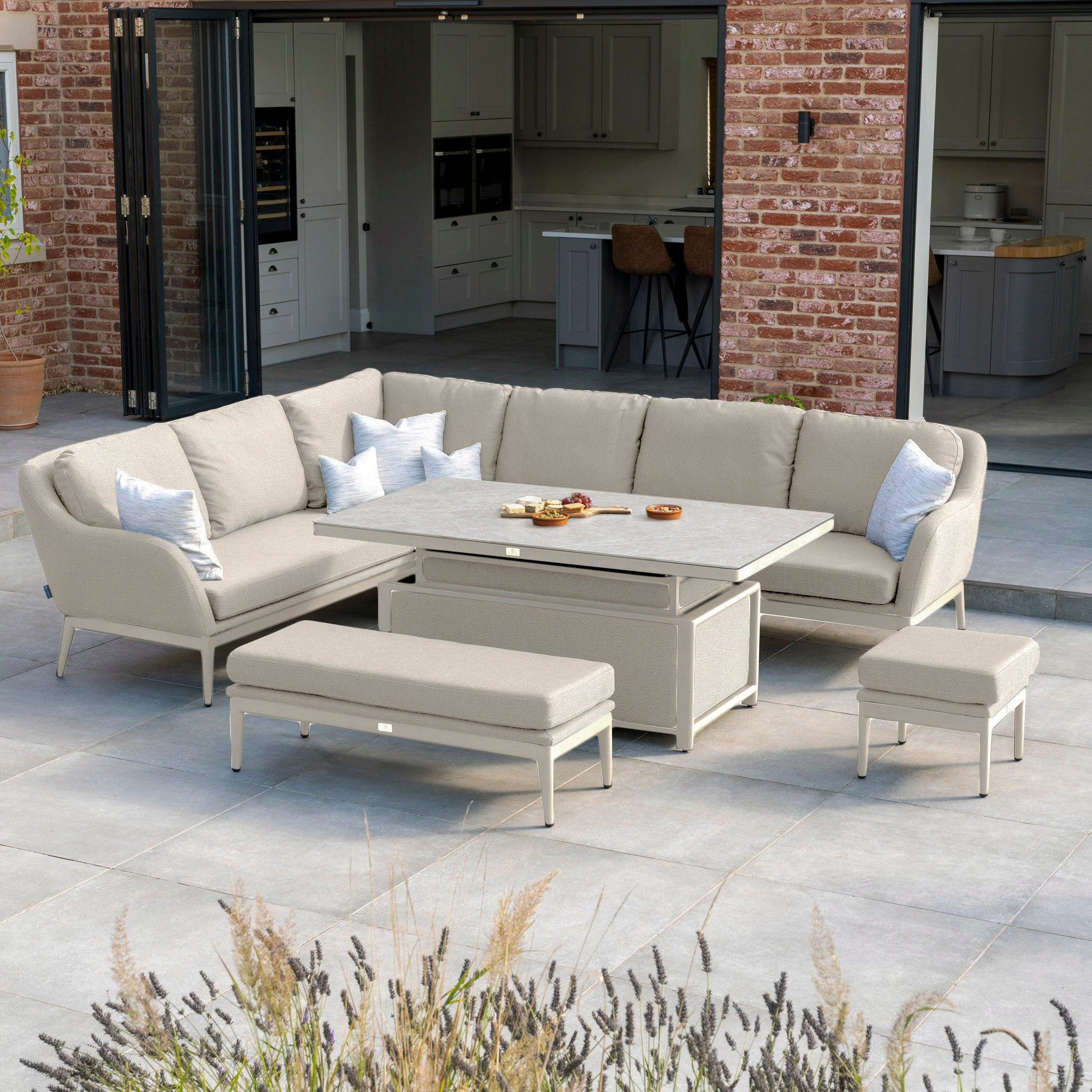 Transform your patio into a charming scene with the Luna Outdoor Fabric Rectangular Corner Dining Set in Fawn, complete with a rising table. This elegant setup, featuring the luxurious fabric and sleek design from Harbour Lifestyle, is perfect for an open brick-walled room, creating a cozy and stylish atmosphere.