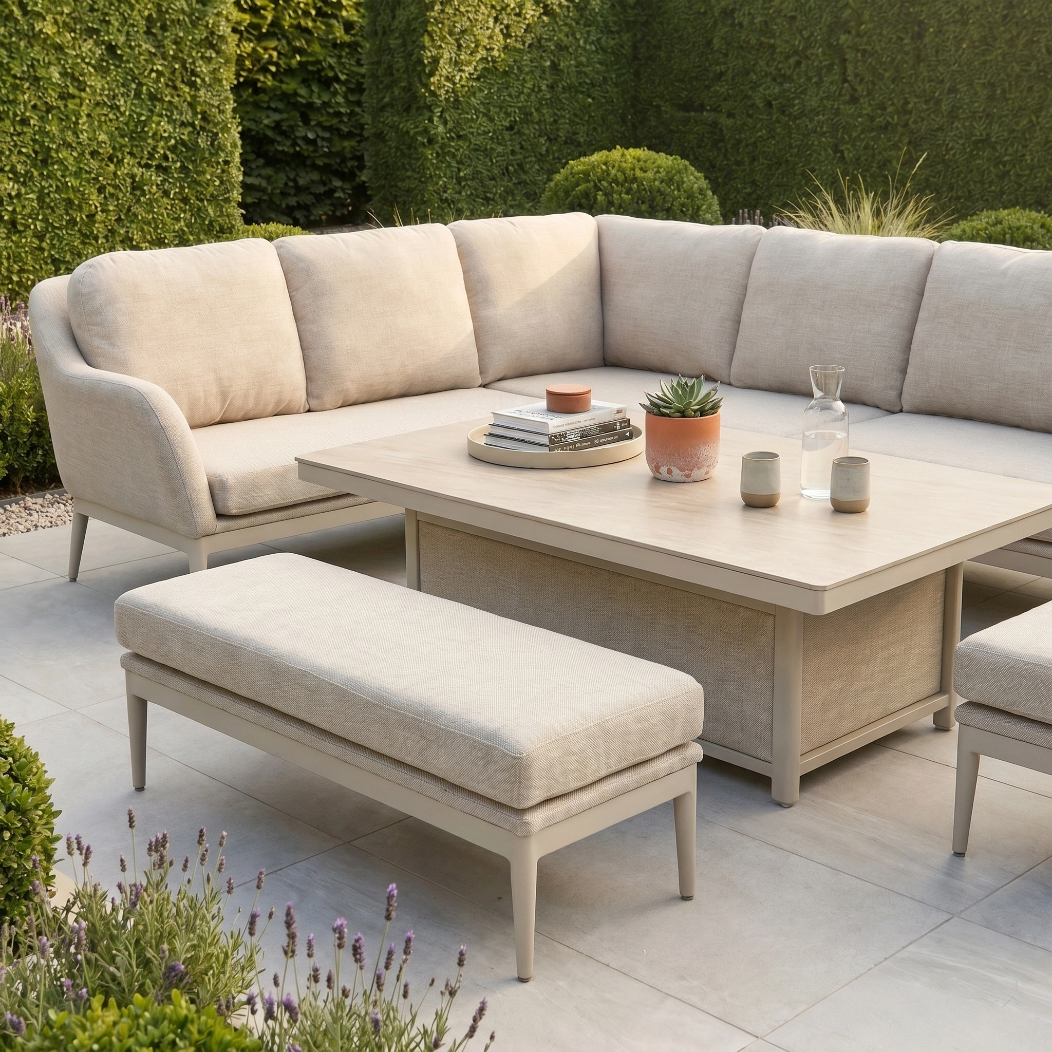 Luna Outdoor Fabric Rectangular Corner Dining Set with Rising Table in Fawn (Left Hand), featuring cozy cushions and a sleek coffee table, nestled among lush greenery.