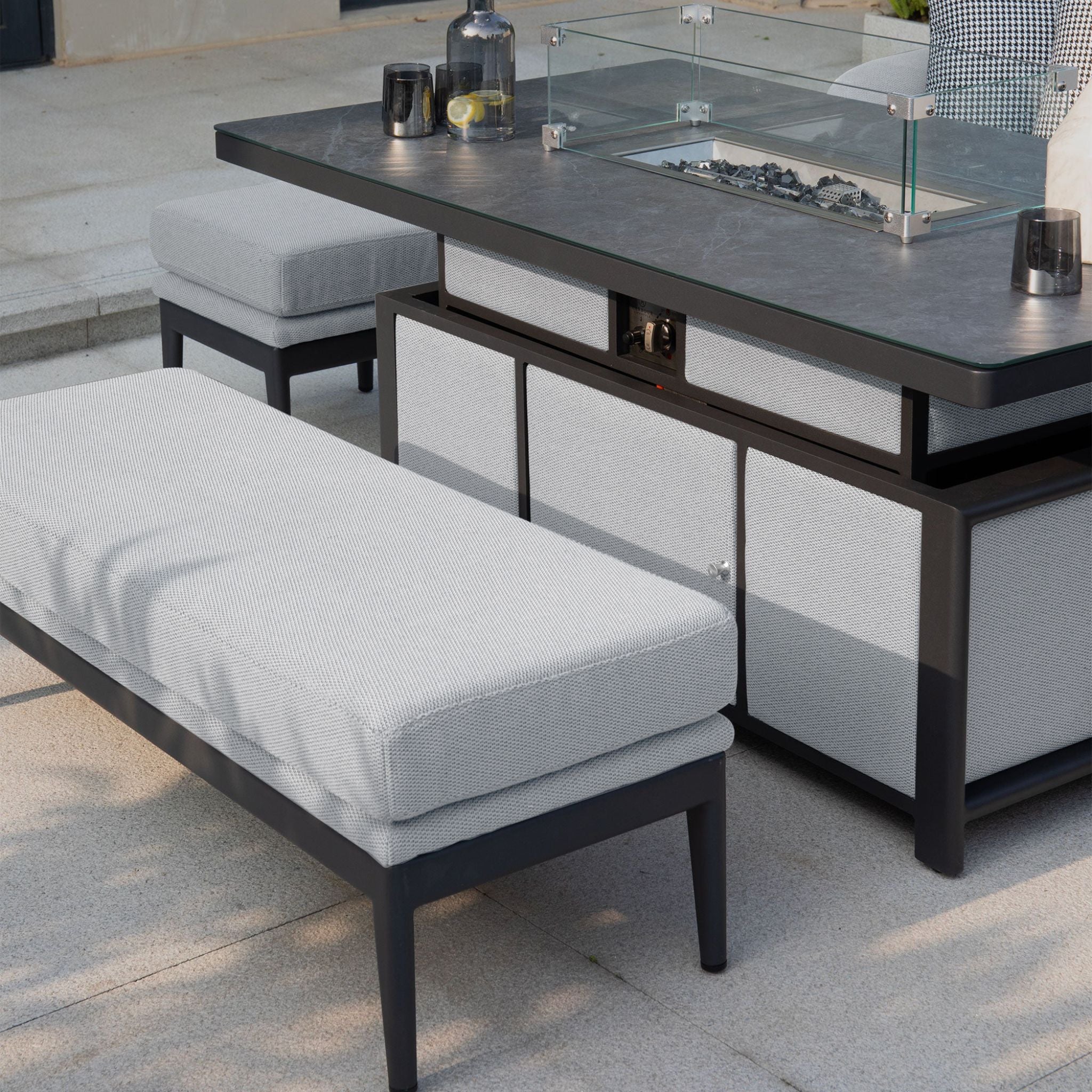 Create a modern outdoor seating area featuring the Luna Outdoor Fabric Rectangular Corner Dining Set with Rising Firepit Table in Oyster Grey (Left Hand), complete with cushioned bench and two ottomans.