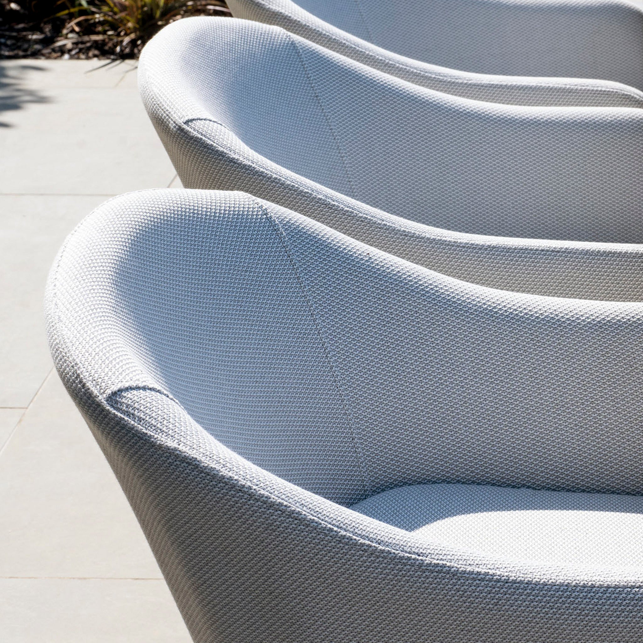 Three stylish Luna chairs in light grey are arranged in a row, perfectly complementing the Luna 4 Seat Round Outdoor Fabric Dining Set with Albatross Table in Oyster Grey for chic outdoor dining.