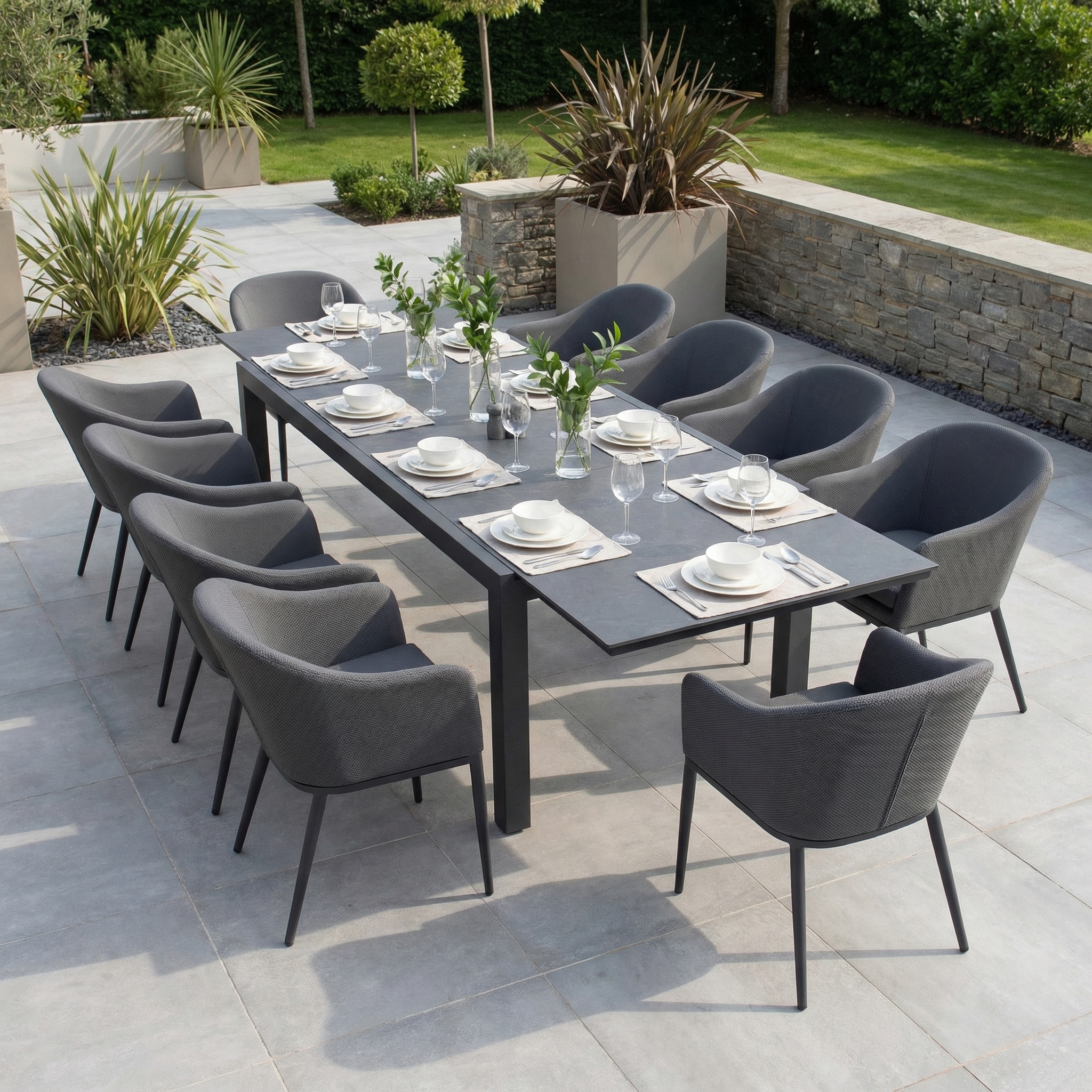 The Luna 10 Seat Outdoor Fabric Extending Ceramic Dining Set in Grey features charcoal chairs and a dark grey extendable ceramic table, all stain-proof, perfect for stylish dining on a tiled patio.
