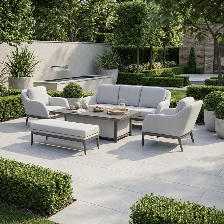 Modern patio featuring the Luna 3 Seat Outdoor Fabric Sofa Set with Rising Table in Oyster Grey, complemented by lush green plants in a landscaped garden setting.