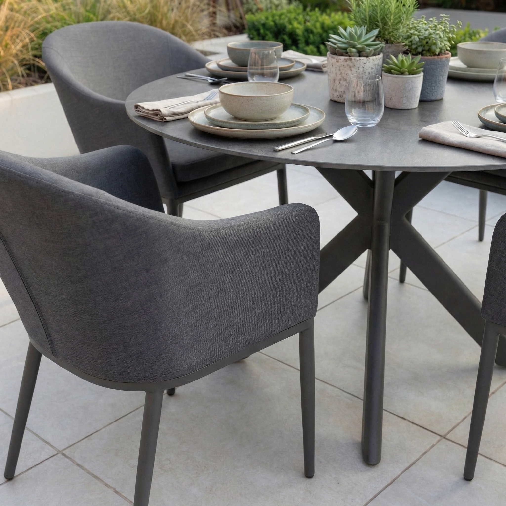 The Luna 4 Seat Round Outdoor Fabric Dining Set with Albatross Table in Grey includes a round patio table and matching chairs, ideal for stylish outdoor dining and entertaining.