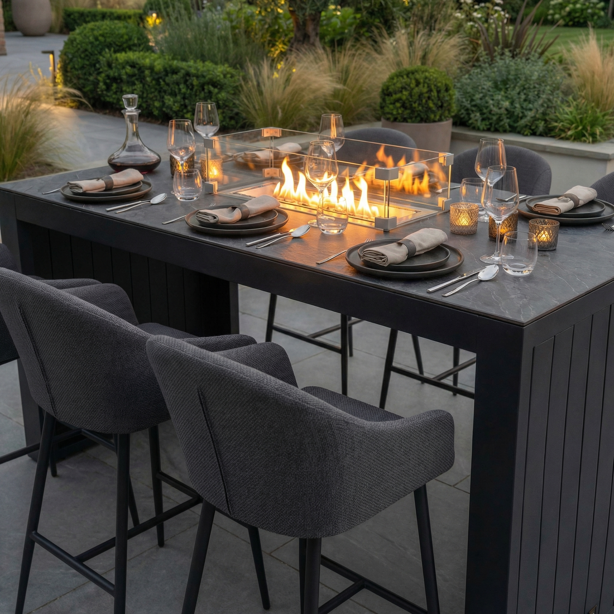 The Luna 6 Seat Outdoor Fabric Ceramic Firepit Bar Set in Grey features a modern dining table with cushioned chairs and a built-in glass fire pit, all crafted from durable outdoor fabric.