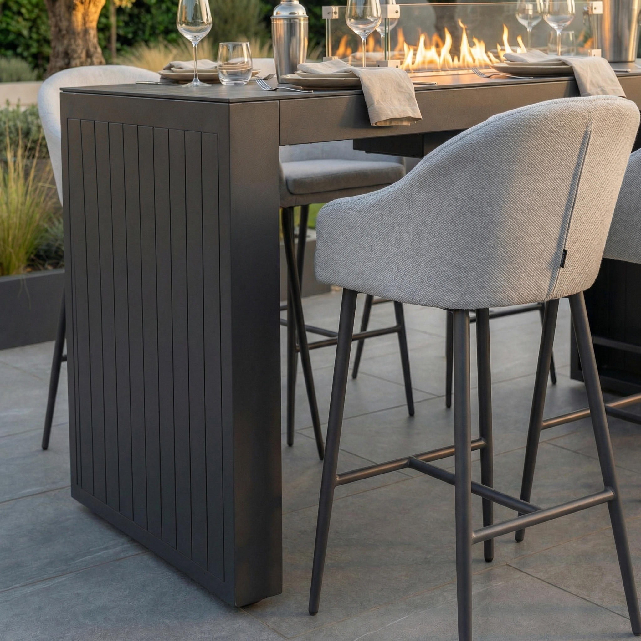 The Luna 6 Seat Outdoor Fabric Ceramic Firepit Bar Set in Oyster Grey features durable all-weather material, gray cushioned bar stools in Luna fabric, and a ceramic fire feature built into the table for lasting style.