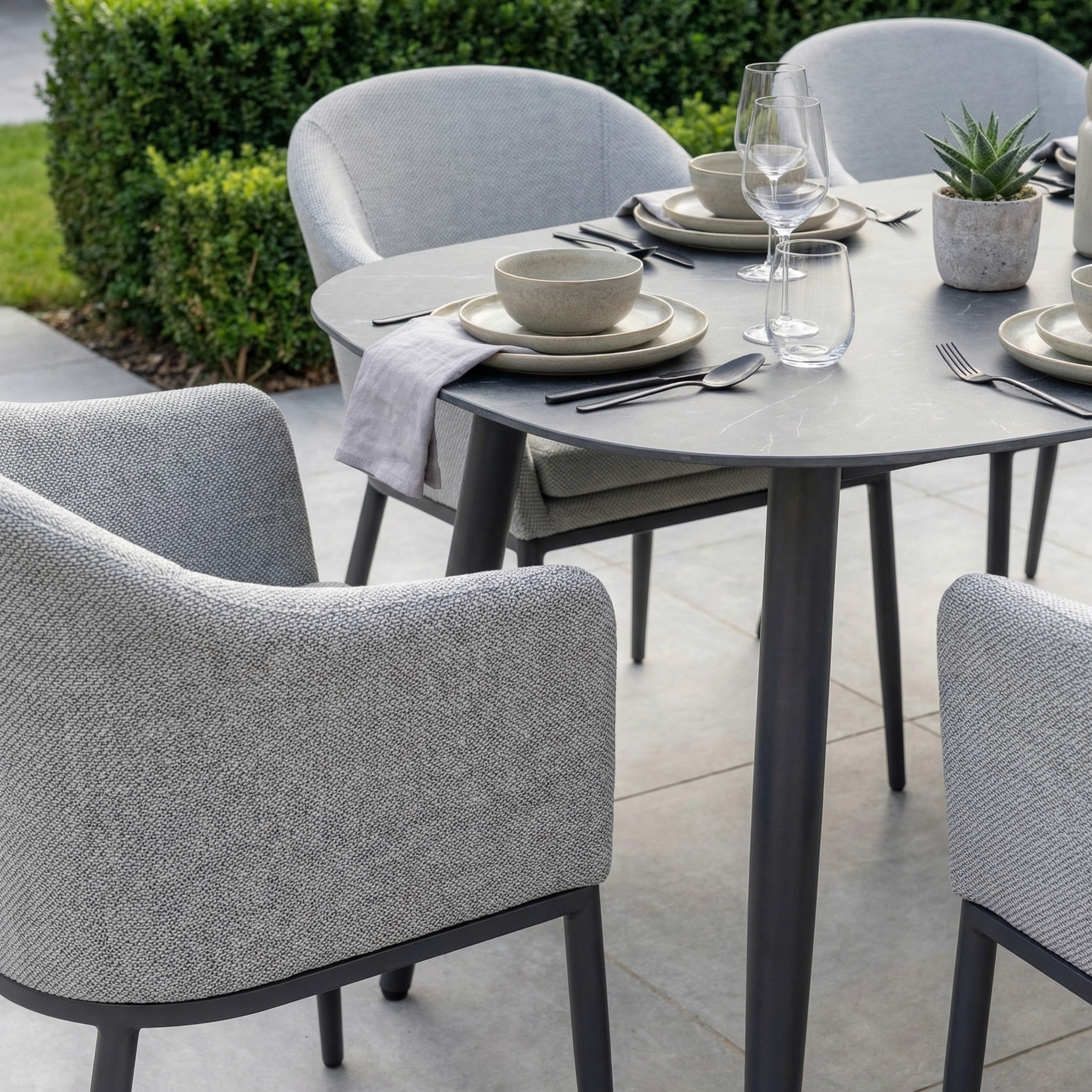 The Luna 6 Seat Outdoor Fabric Oval Ceramic Dining Set in Oyster Grey features six cushioned chairs in weather-resistant fabric and a durable ceramic table, bringing lasting style to any outdoor dining space.