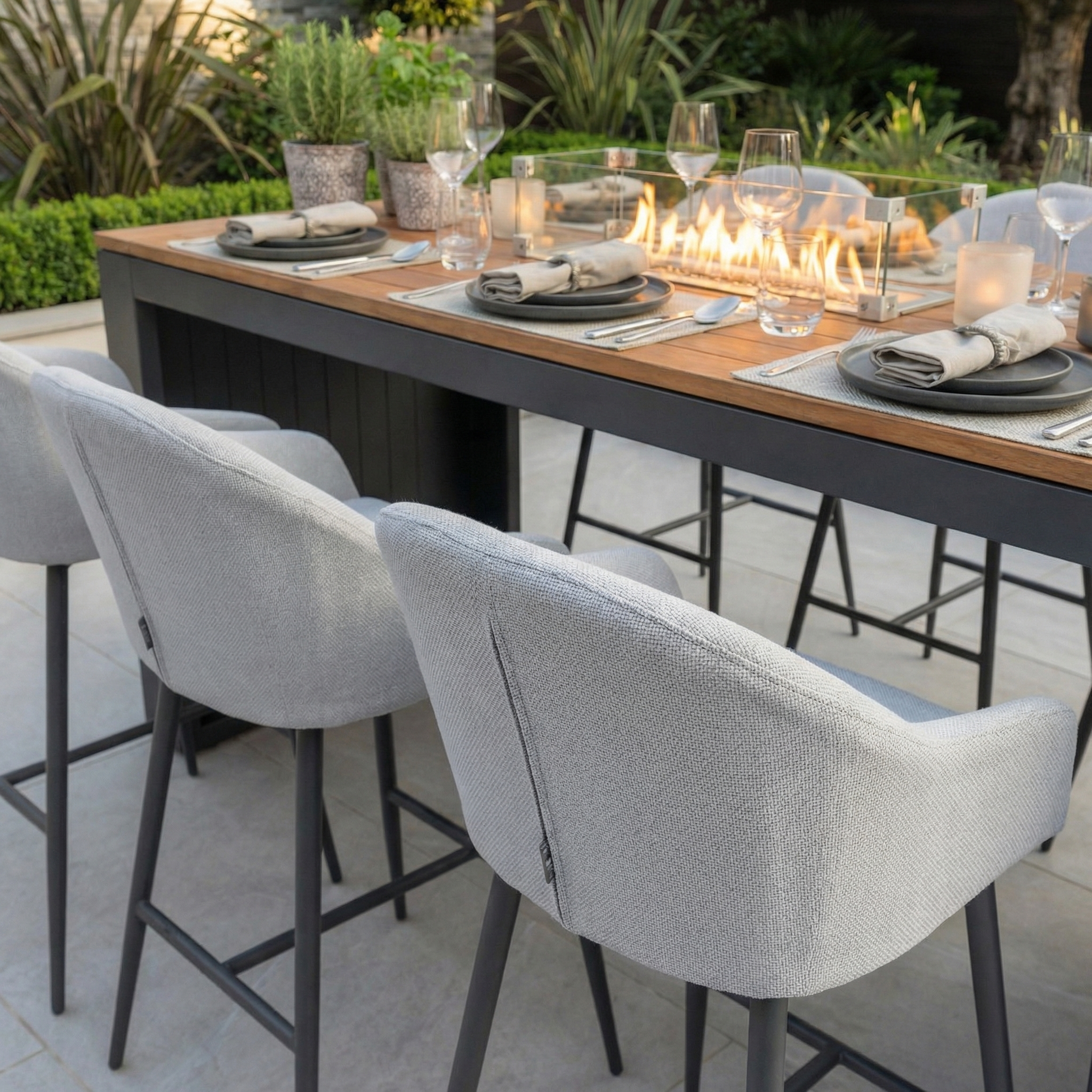 The Luna 6 Seat Outdoor Fabric Teak Firepit Bar Set in Oyster Grey features stylish gray chairs in Luna fabric, a teak table with integrated firepit, and durable materials—an all-weather outdoor set perfect for gatherings.