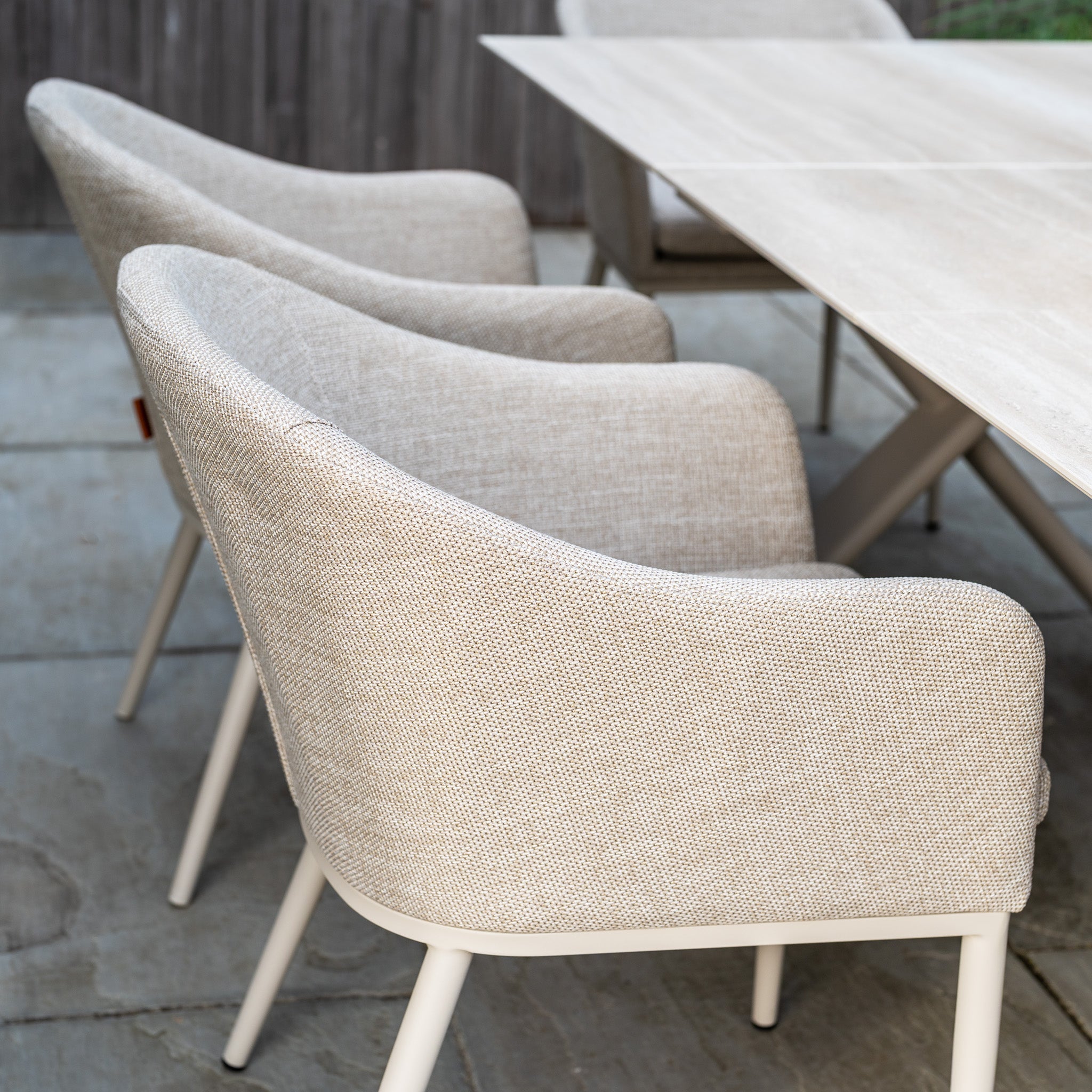 The Luna 6 Seat Outdoor Fabric Dining Set with Albatross Extending Table in Fawn is arranged on a stone patio.