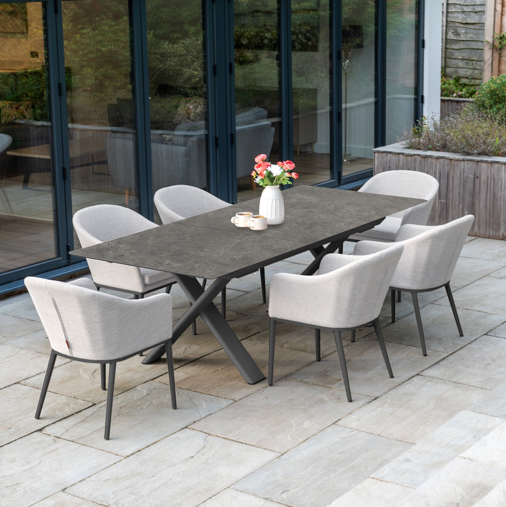 The Luna 6 Seat Outdoor Fabric Dining Set with Albatross Extending Table in Oyster Grey features six light gray chairs and a dark extending table, perfect for stylish dining on your patio.