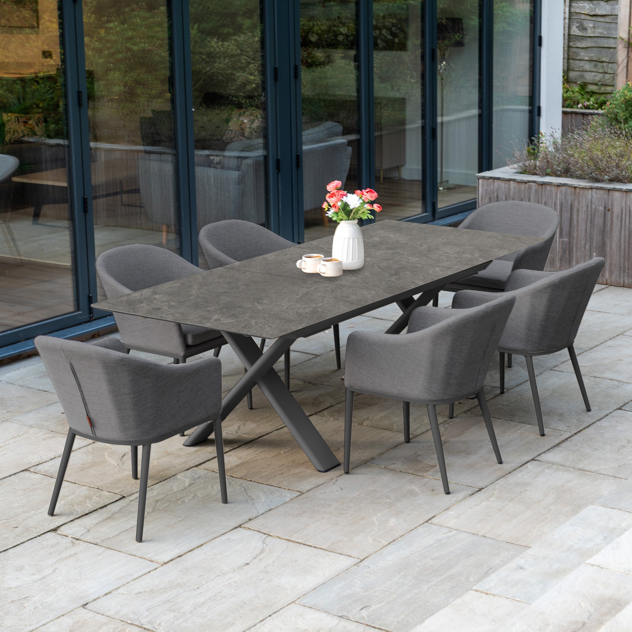 The Luna 6 Seat Outdoor Fabric Dining Set features six gray chairs and a grey Albatross extending table—stylish, all-weather patio furniture ideal for modern outdoor dining.