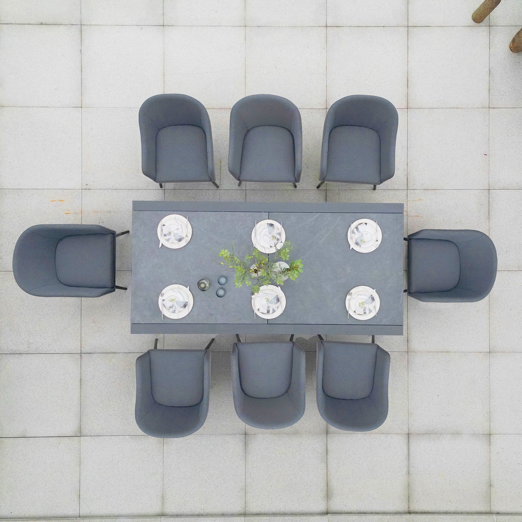 Top view of the Luna 8 Seat Outdoor Fabric Extending Ceramic Dining Set in Grey, showcasing rust-proof construction with elegantly arranged gray chairs and plates on a tiled patio.