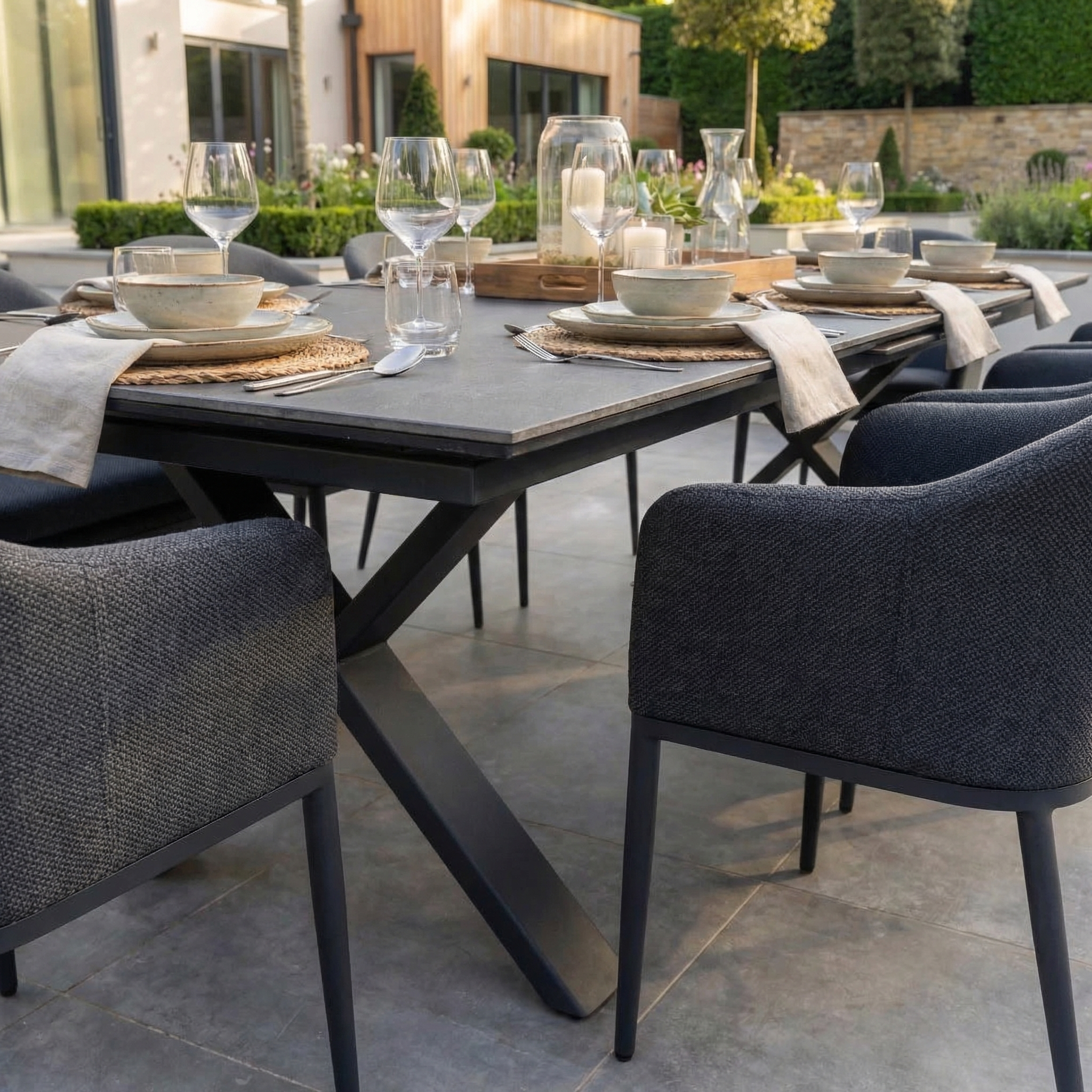 The Luna 8 Seat Outdoor Fabric Dining Set with Albatross Extending Table in Grey features cushioned, all-weather chairs and a spacious table, perfect for alfresco dining with plates, glasses, and candles on your patio.
