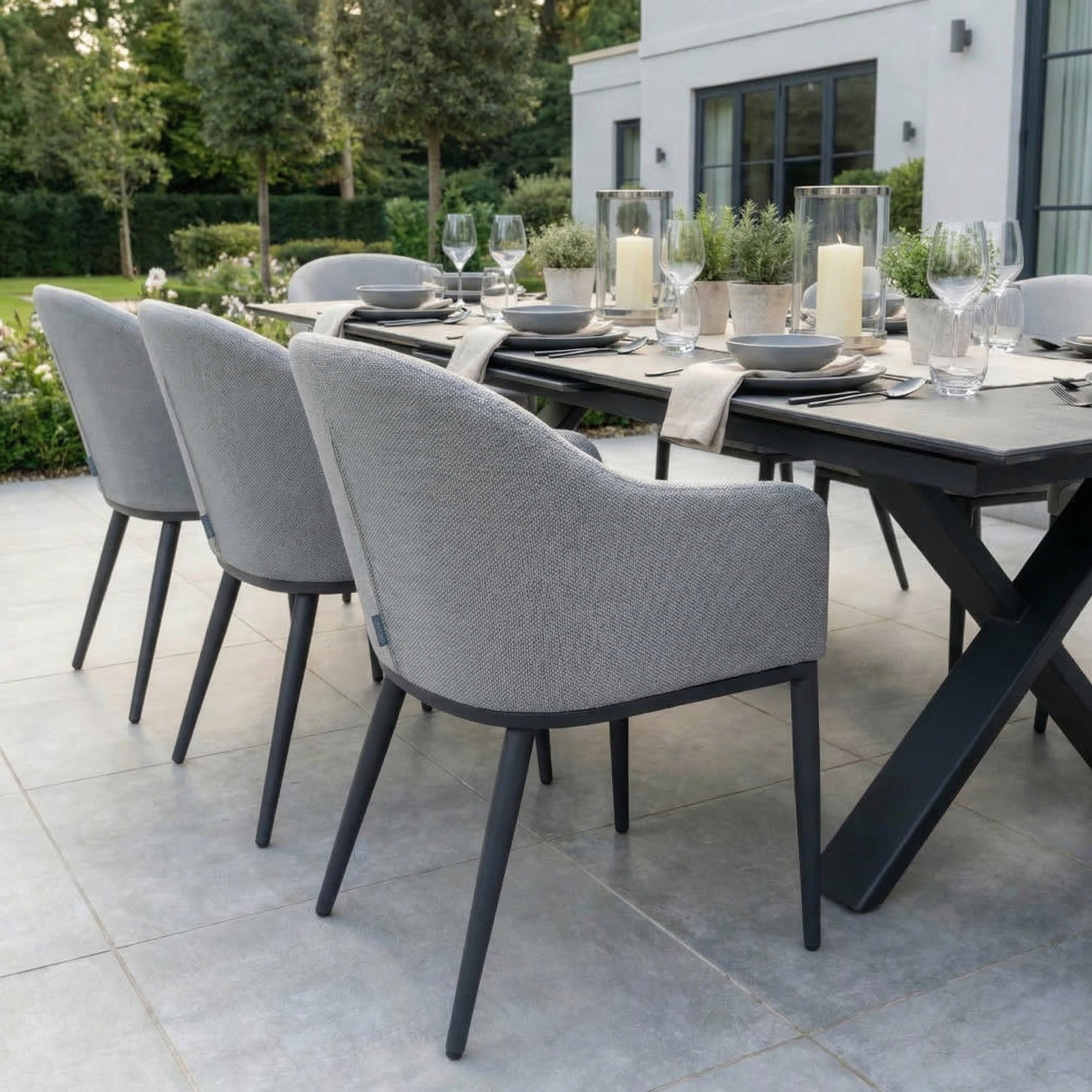 Host stylish outdoor gatherings with the Luna 8 Seat Outdoor Fabric Dining Set featuring the Albatross Extending Table in Oyster Grey, perfectly set for dining with plates, glasses, and candles.