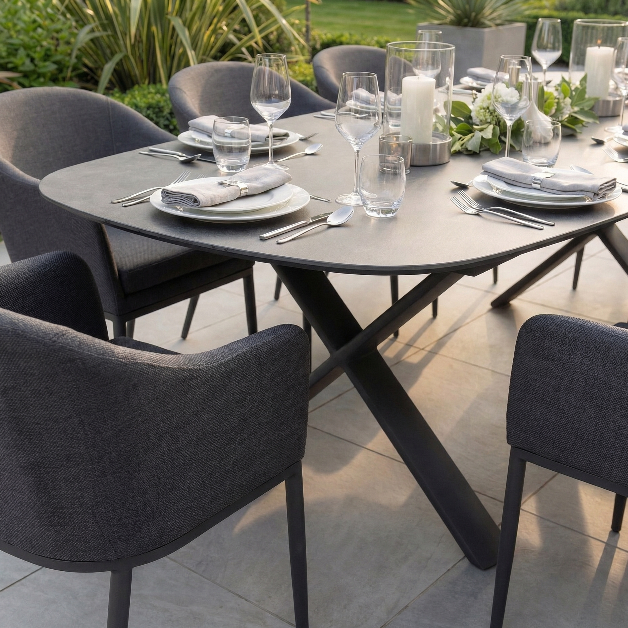 The Luna 8 Seat Outdoor Fabric Oval Dining Set with Albatross Extending Table in Grey features stylish, UV-resistant seating for eight—perfect for patio dining with included gray chairs, white plates, and glassware.