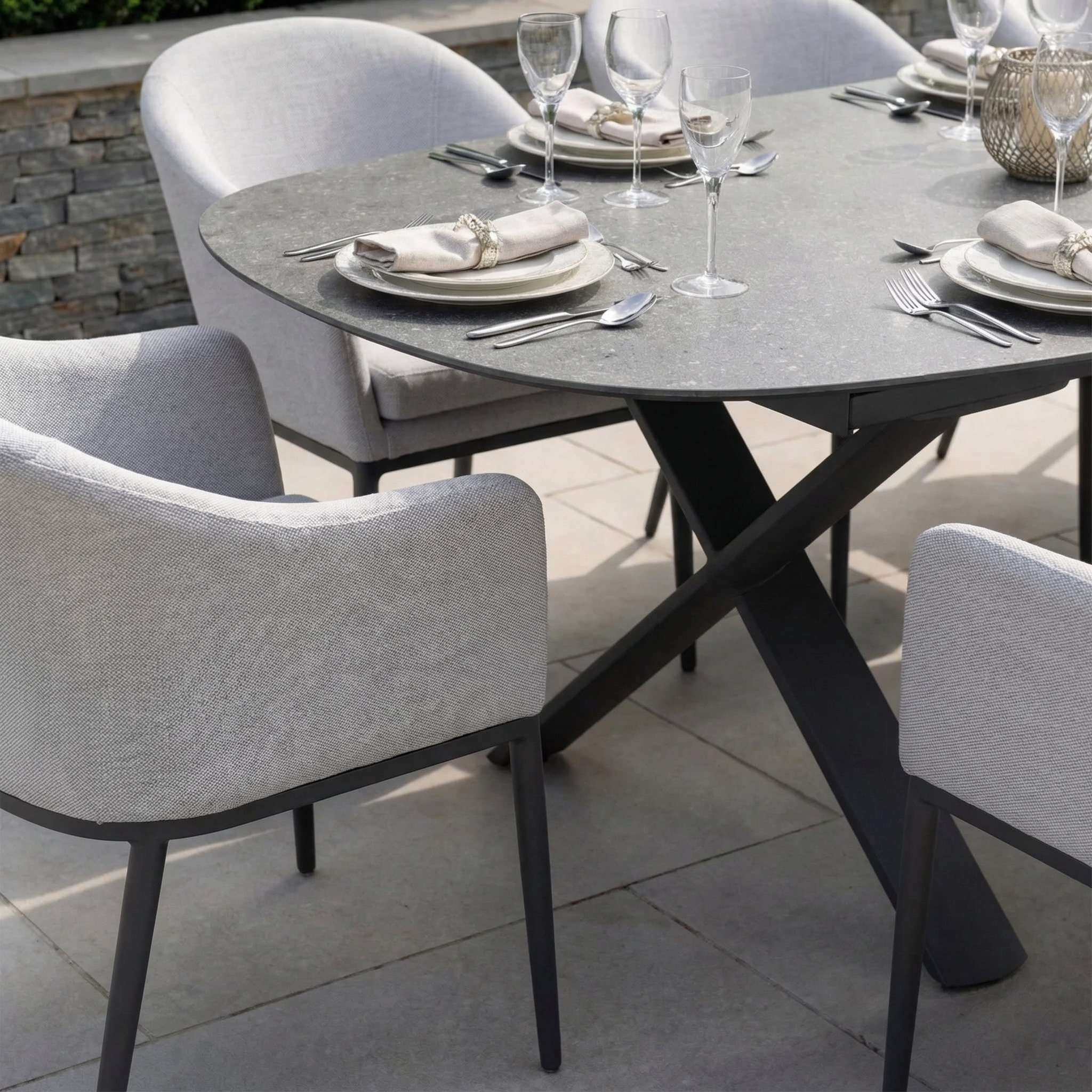 The Luna 8 Seat Outdoor Fabric Oval Dining Set with Albatross Extending Table in Oyster Grey includes UV-resistant cushioned chairs, perfect for outdoor dining. Plates, cutlery, and wine glasses are also included.