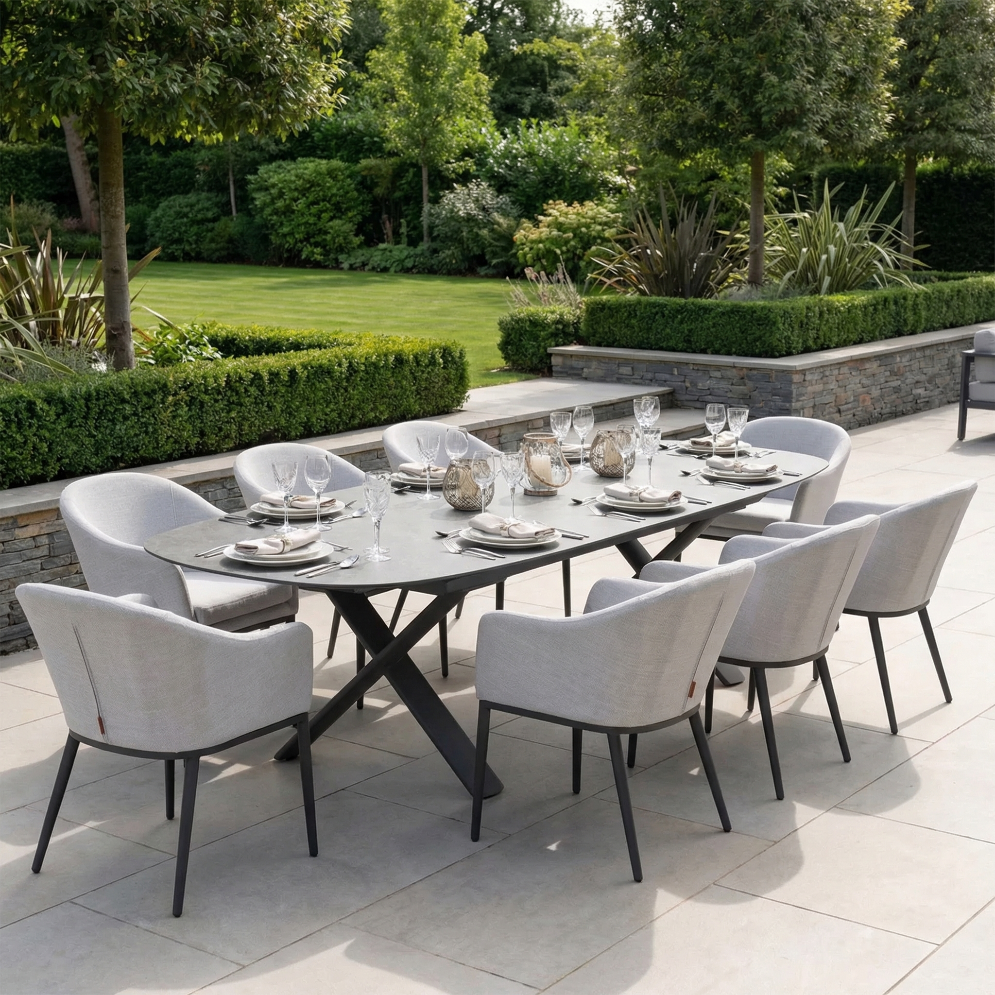 The Luna 8 Seat Outdoor Fabric Oval Dining Set with Albatross Extending Table in Oyster Grey features eight chairs with UV resistant cushions, perfect for patio dining surrounded by greenery.