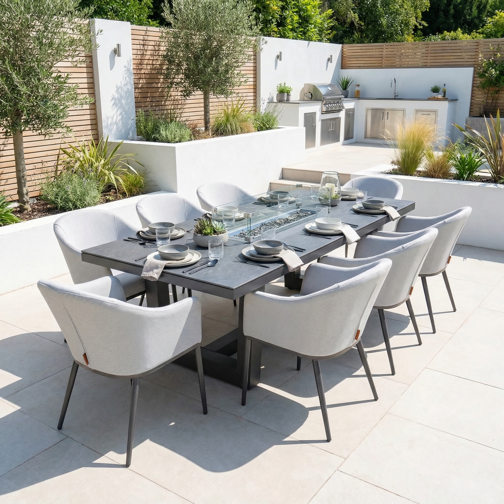 Modern outdoor dining area with the Luna 8 Seat Outdoor Fabric Rectangular Ceramic Firepit Dining Set in Oyster Grey and a built-in grill on a landscaped patio.