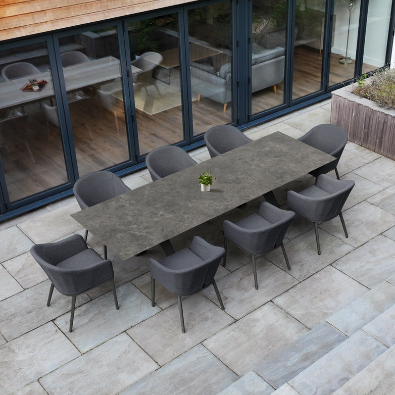 Outdoor patio with the Luna 8 Seat Outdoor Fabric Dining Set featuring the Albatross Extending Table in Grey and eight all-weather grey chairs, accented by a small plant centerpiece.