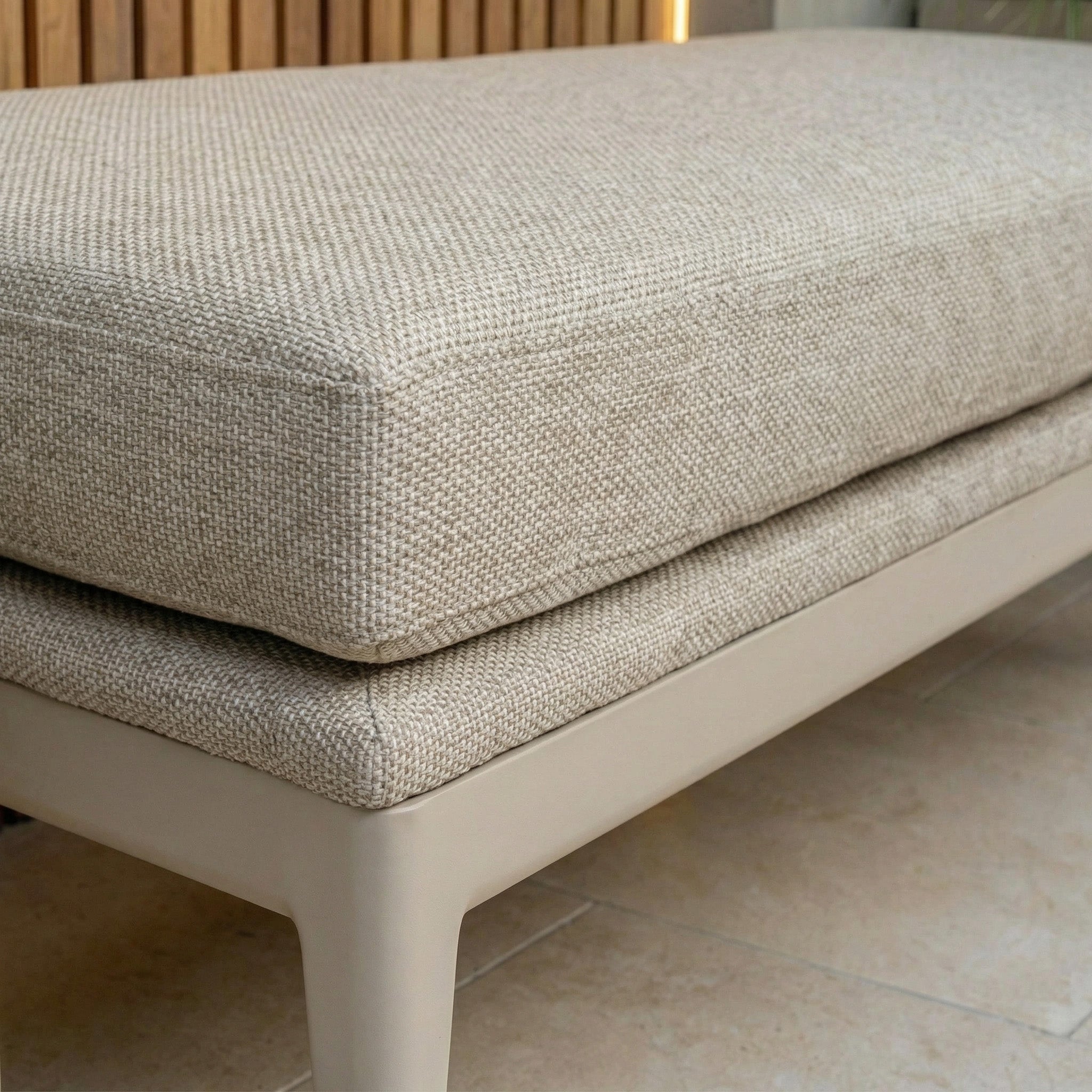 Close-up of the Luna Bench in Fawn, featuring a beige cushion and light wooden frame on a tiled floor—ideal outdoor seating for any space.