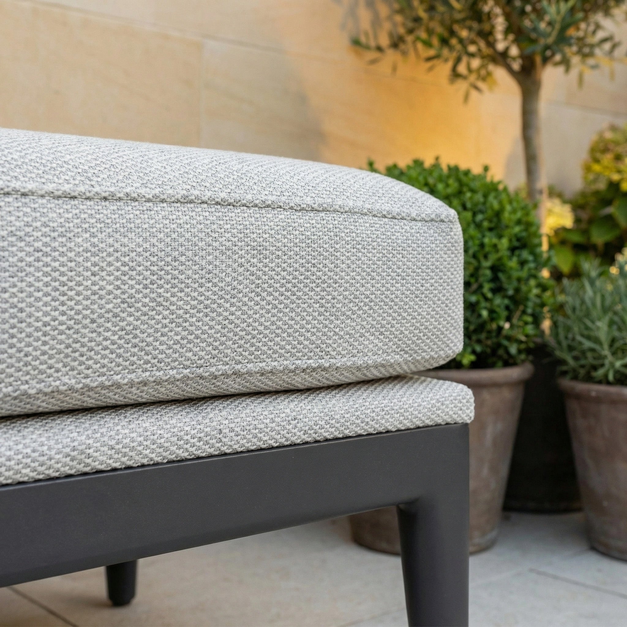 Close-up of a beige outdoor cushion on the Luna Bench in Oyster Grey, with potted plants behind—perfect for stylish, comfortable outdoor seating.