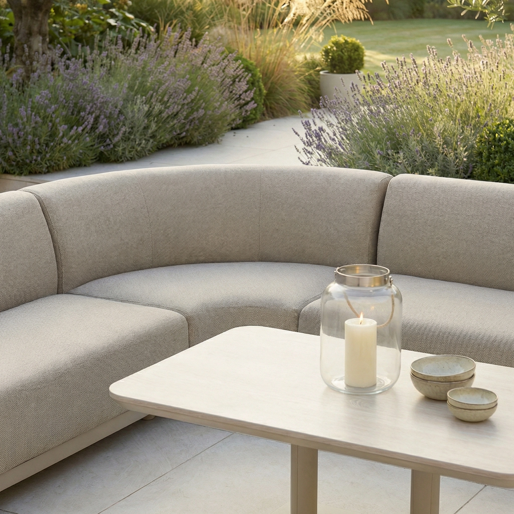 The Luna Outdoor Fabric Curved Corner Sofa Set with Altura Rising Table in Fawn offers stylish, all-weather comfort for your garden—ideal for relaxing outdoors among lush greenery.