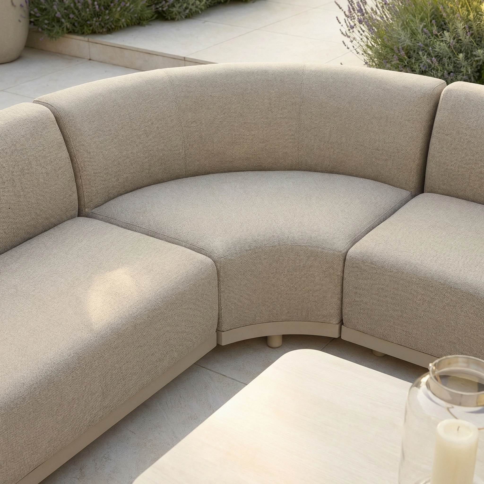 The Luna Outdoor Fabric Curved Corner Sofa Set with Altura Rising Table in Fawn creates an inviting all-weather setup on the patio, featuring textured cushions and a stylish beige design for your garden.