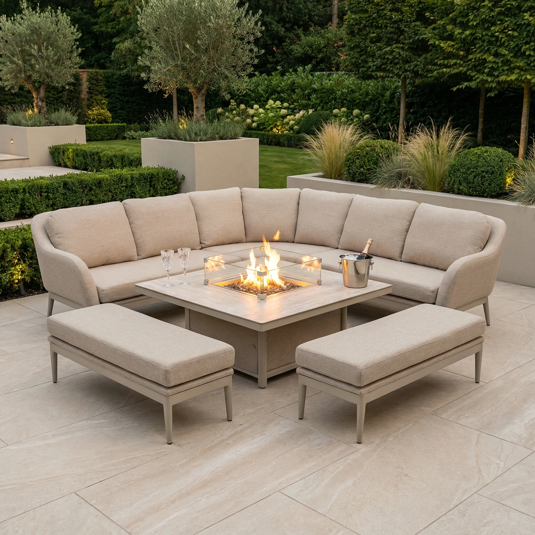 Landscaped garden patio featuring the Luna Deluxe Outdoor Fabric Square Corner Dining Set with Rising Firepit Table in Fawn.