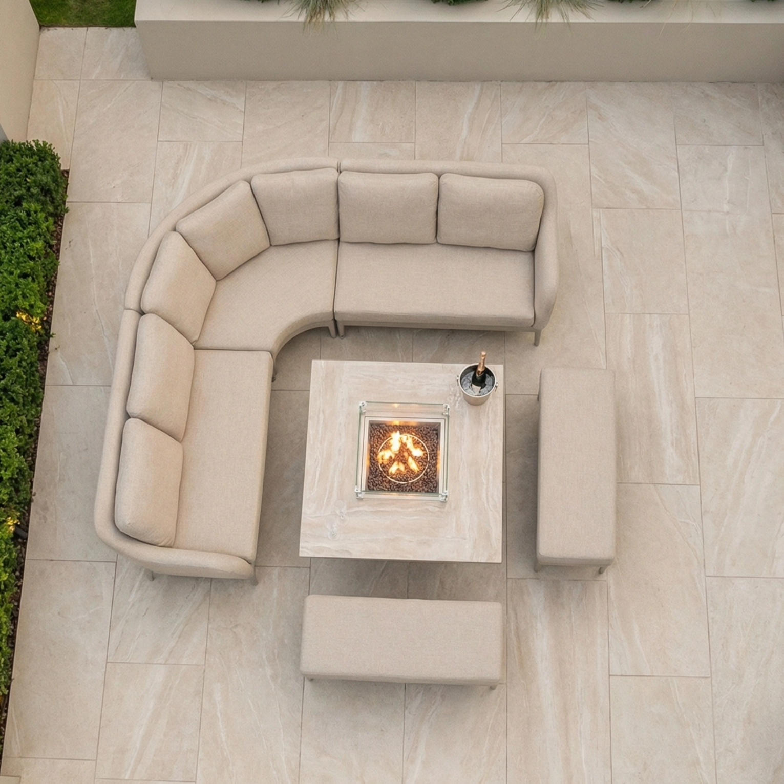 The Luna Deluxe Outdoor Fabric Square Corner Dining Set in Fawn with Rising Firepit Table sits on a tiled patio, complemented by benches.