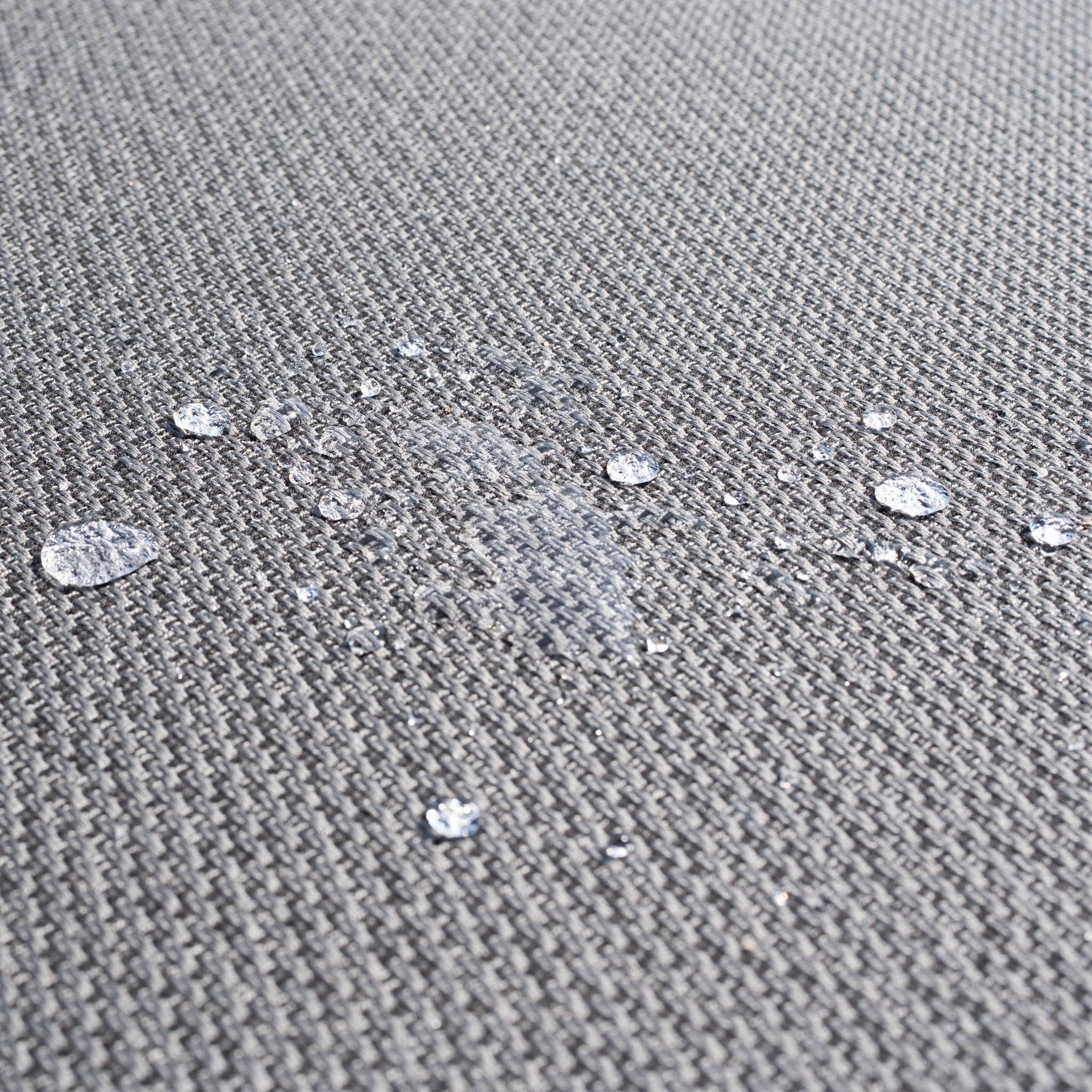 Water droplets on the Luna Outdoor Fabric Deluxe Sun Lounger with Bolster Cushion in Grey show its water resistance and durable, solution-dyed acrylic fabric—perfect for outdoor use.