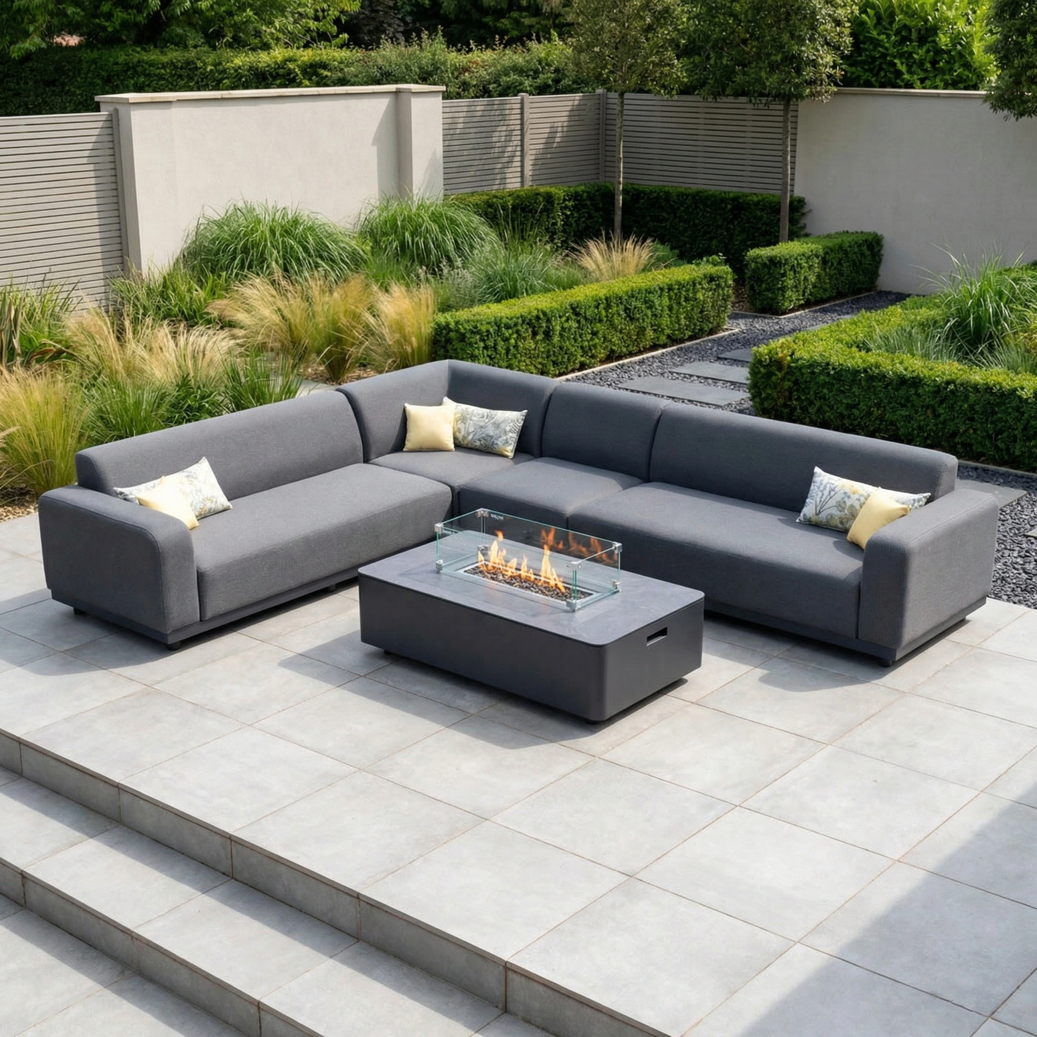 The Luna Outdoor Fabric Large Corner Group Set with Firepit Coffee Table in Grey offers durable, stylish relaxation on your modern patio, featuring all-weather comfort and plush pillows surrounded by greenery.