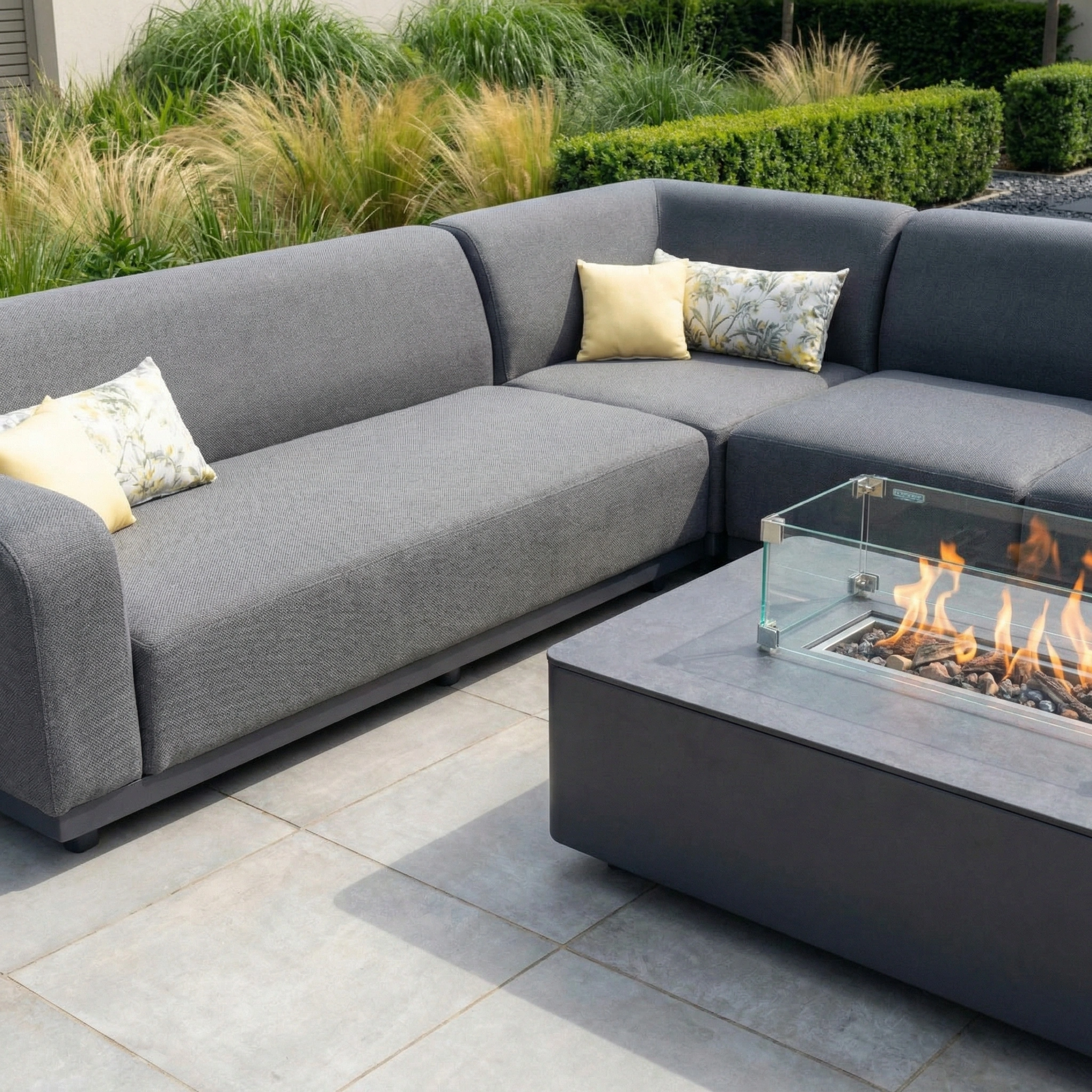 Modern patio featuring the Luna Outdoor Fabric Large Corner Group Set with Firepit Coffee Table in Grey, complete with yellow pillows, on tiled flooring.