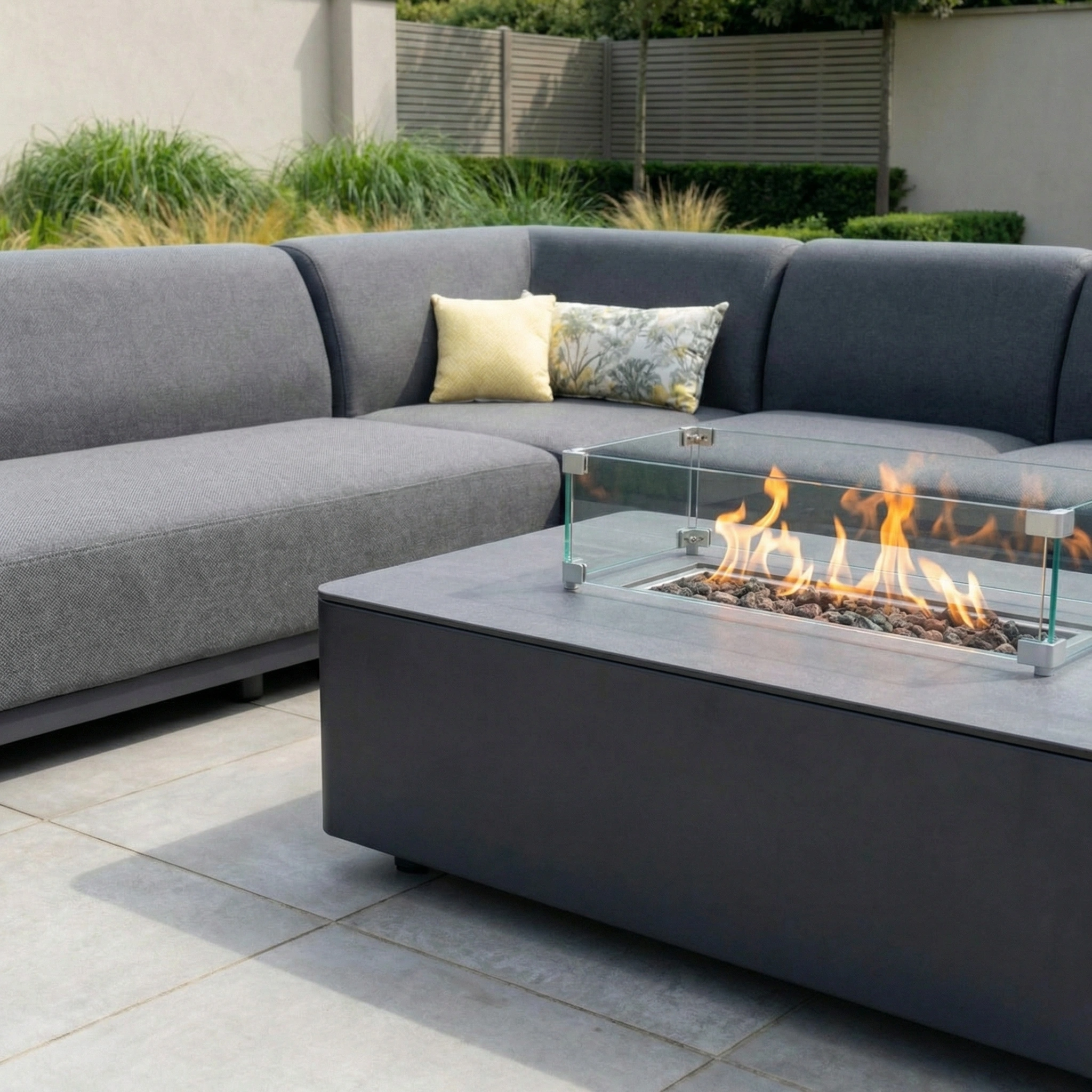 Modern patio featuring the Luna Outdoor Fabric Large Corner Group Set in grey with a firepit coffee table, styled with yellow and patterned pillows for a fresh look.